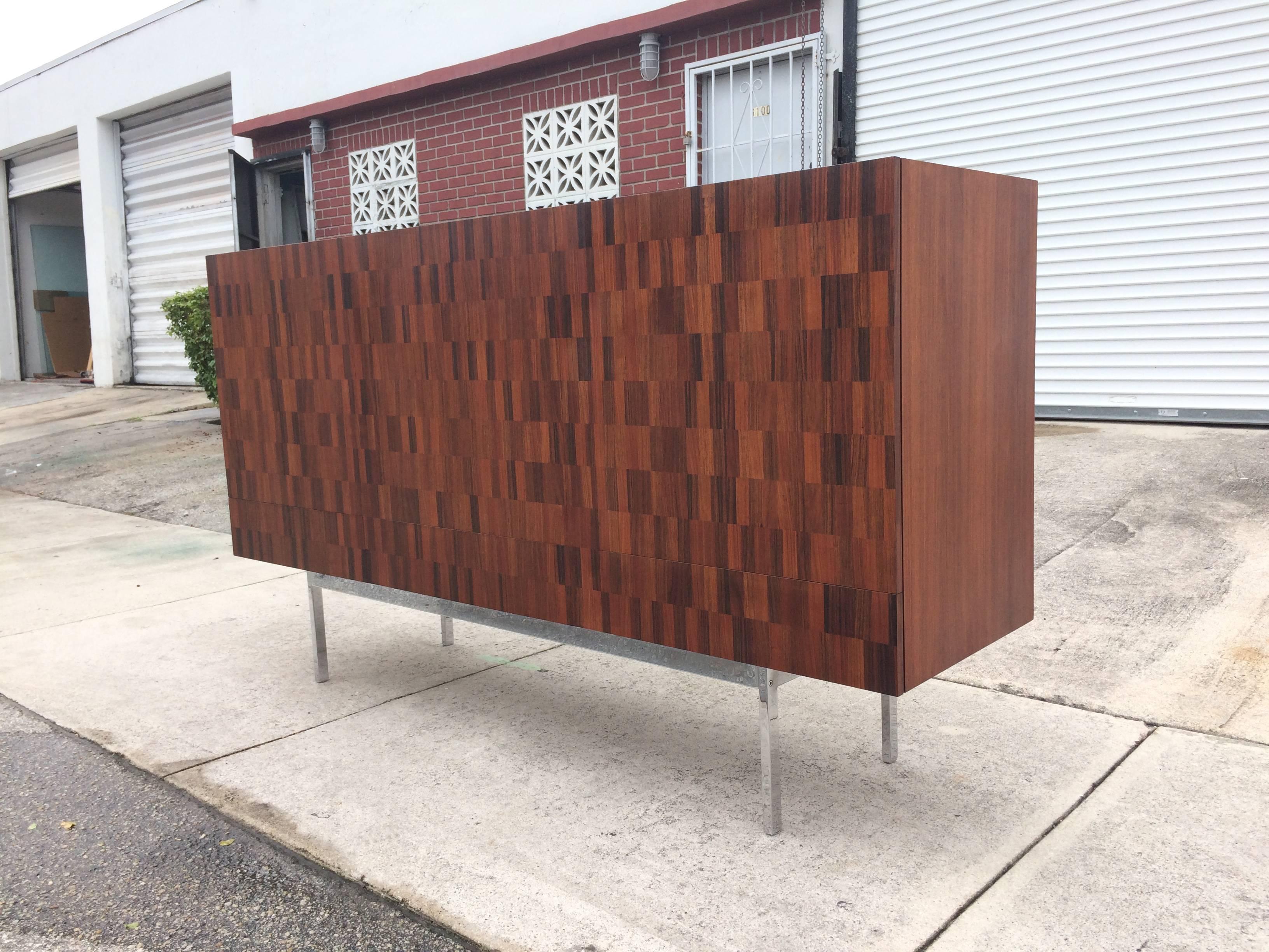 Sideboard on chromed steel base with parquet design. Sideboard has three drawers and three doors. Behind the doors are five pull-out trays and two shelves.