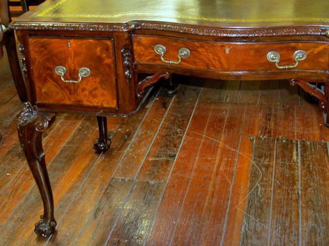 Exceptional quality old English hand-carved solid mahogany Chippendale style leather top writing table or desk.

Please note fabulous flame mahogany drawer fronts and hand-carved motifs. Also note the superb hand-carved edge, corner frets and