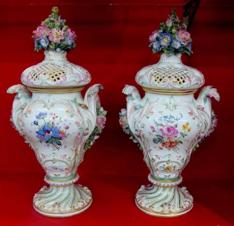 Pair of exceptional quality 18th century Antique Meissen hand painted porcelain potpourri urns or vases with period bocage lids.

Note the exceptional bocage work on the floral clusters atop each lid. The painted pastoral landscapes on the obverse