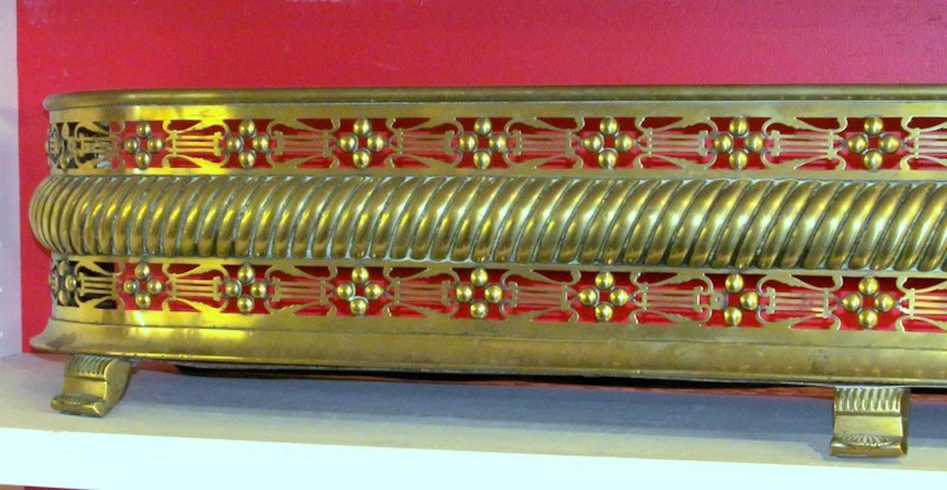 Fabulous antique George III pierced brass fireplace fender. Please note wonderfully pierced design showing lyres and rope turned middle. Also, this fender has its original cast brass feet and steel pan.