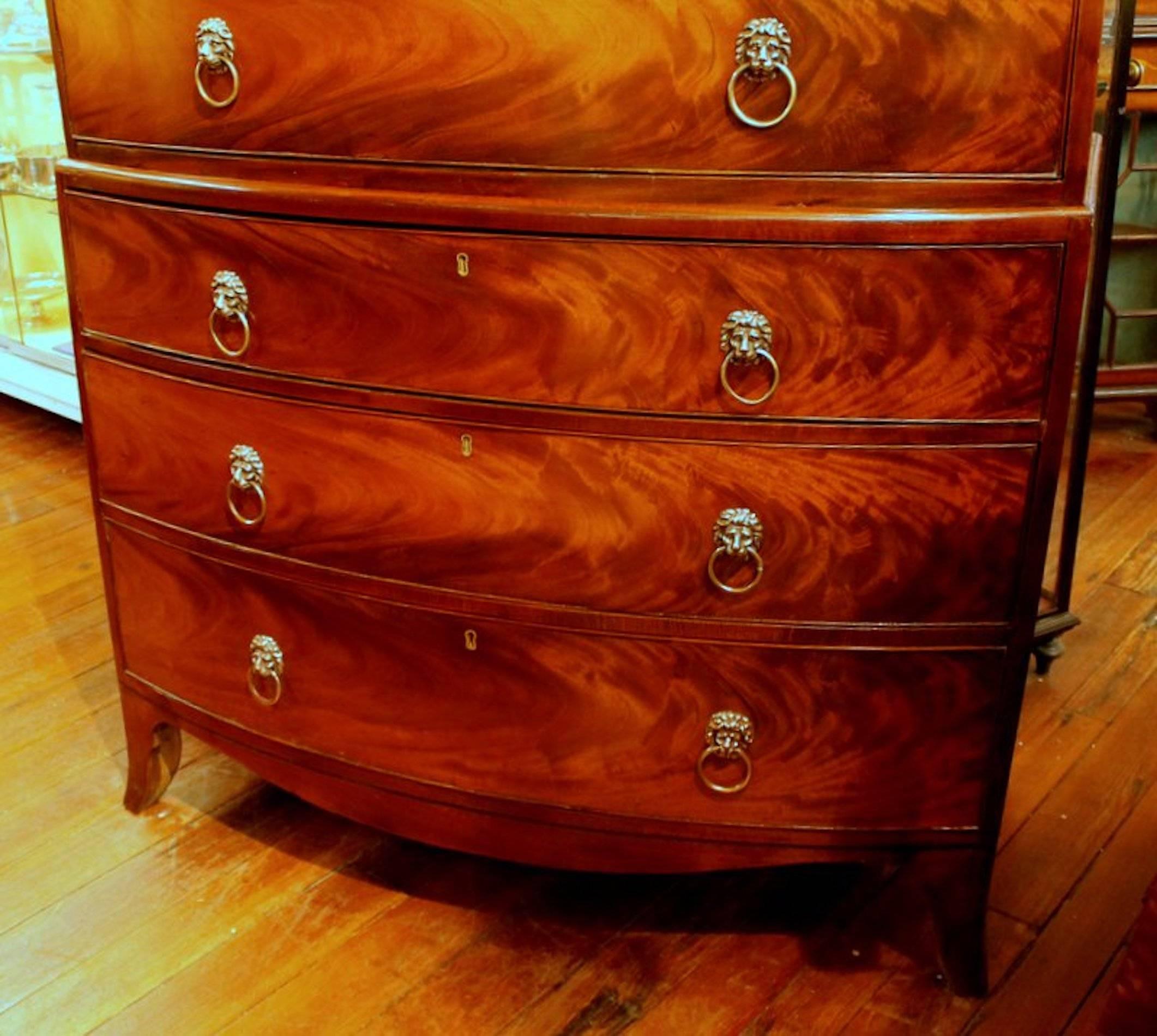Magnificent quality antique English bookmatched crotch mahogany George III bow-front chest on chest. Please note the fabulous bookmatched mahogany veneers across the front of the drawers - superior quality and bow-fronted!

The lion head pulls are