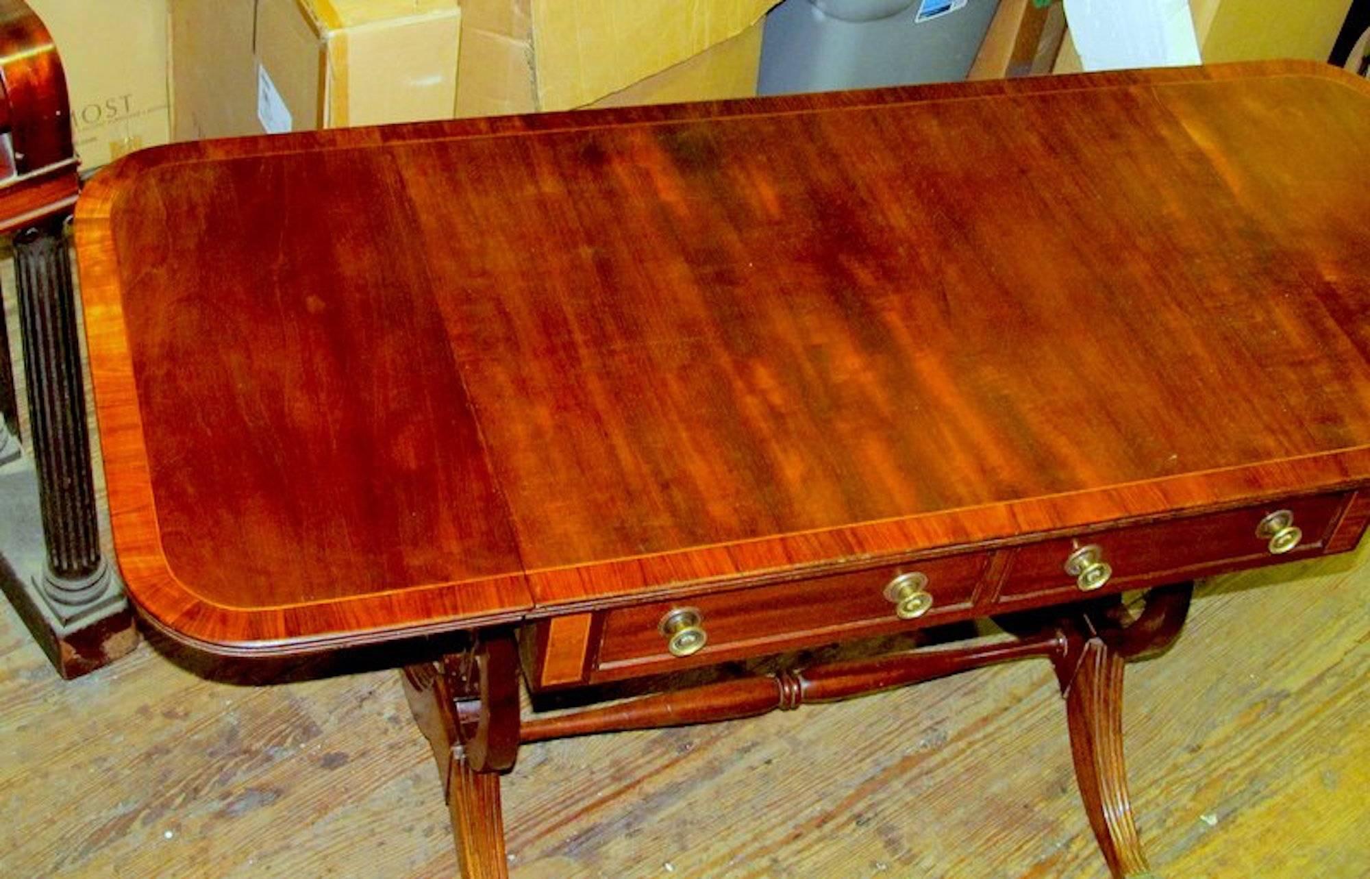 Fine et rare table de canapé Regency en acajou marqueté de la période George IV, avec de beaux supports latéraux en forme de lyre et des pieds évasés terminés par des roulettes en laiton moulé.

Dimensions fermées : 29 1/2