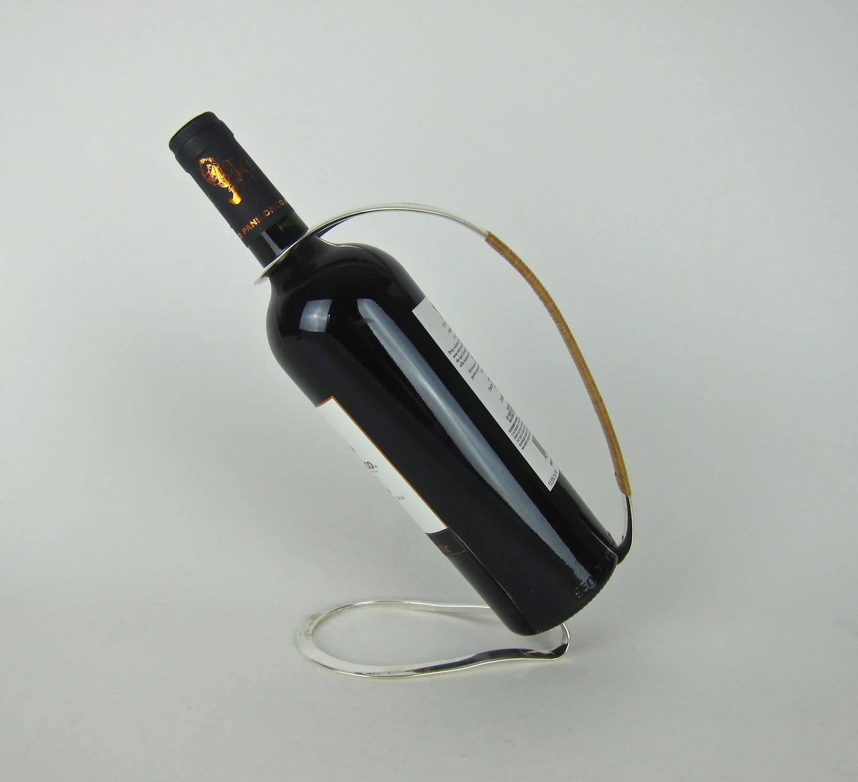 A Mid-century German wine bottle holder in silver plate with a cane wrapped handle. Stamped with the "EL" and crown Eisenberg-Lozano, Inc. of New York trademark. The holder is in good condition, measuring 9 in. H x 3.75 in. W.

Arthur