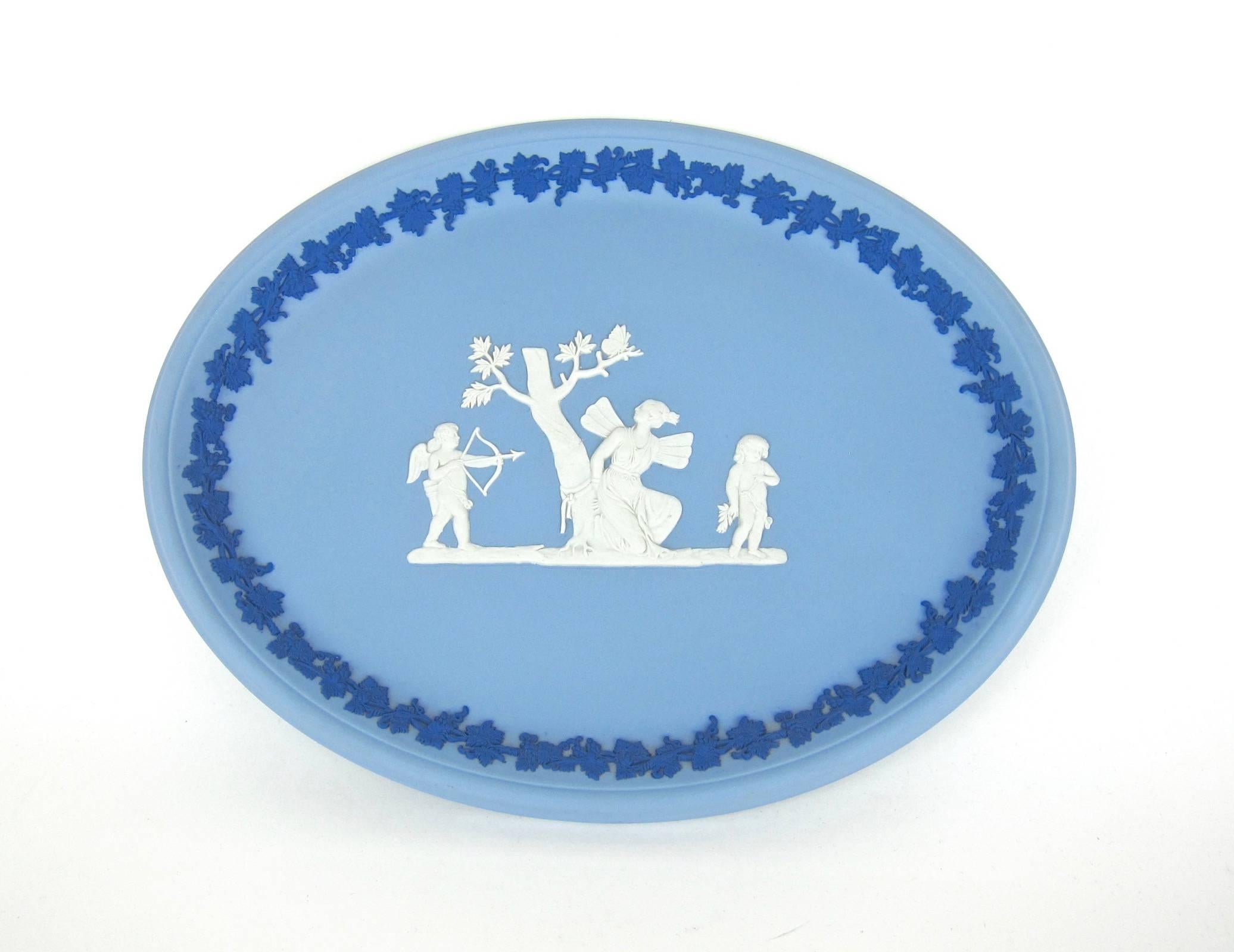 An English Wedgwood oval tray in solid tri-color Jasperware designed to decorate a tabletop, vanity, or for display on a wall. The pale blue body is decorated with a bas-relief scene depicting Psyche bound alongside Cupid drawing his bow. A