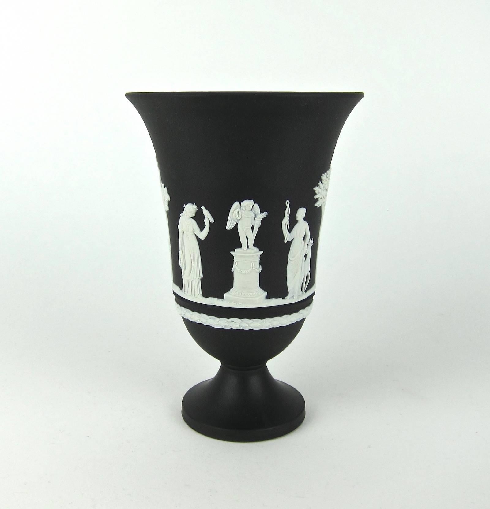 A handsome vintage Wedgwood Arcadian flaring and footed vase decorated with Neoclassical “sacrifice” figures and trees in white bas-relief on solid black jasper. The vase was made in England in 1976 and comes from an important California collection