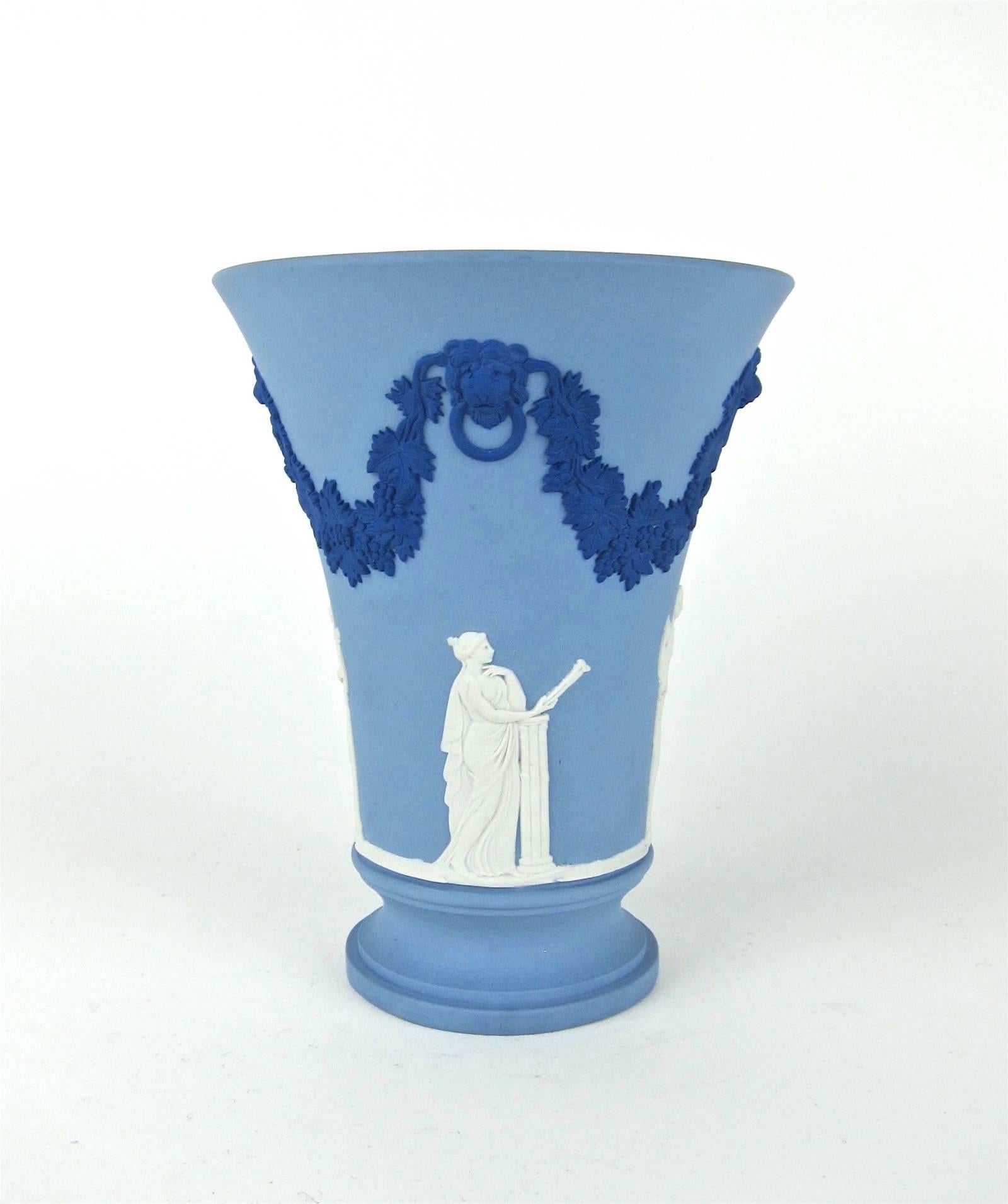 A handsome flaring vase in tri-color jasperware from Wedgwood of England, signed by Lord Wedgwood in 1988. The vase is a solid pale blue with neoclassical bas-relief ornament of grapevine festoons and lion heads in a darker Portland Blue over four