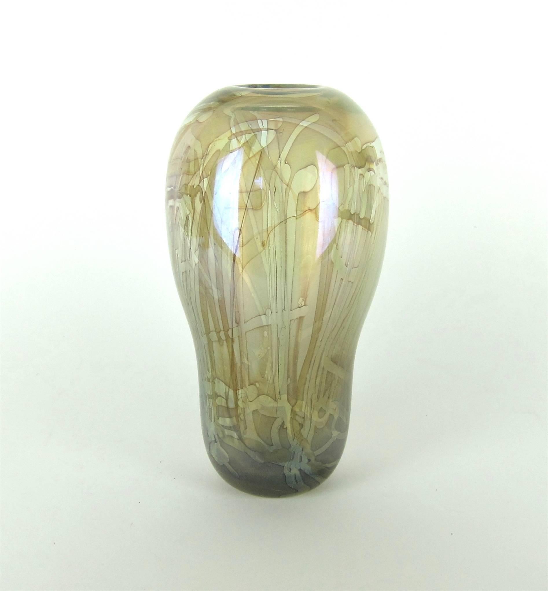A signed and numbered American studio glass vase by Robert (Bob) William Bartlett (b. 1948) in neutral greens and browns with an overall iridescence. Much of the design is transparent with contrasting darker designs trailing down the body toward an