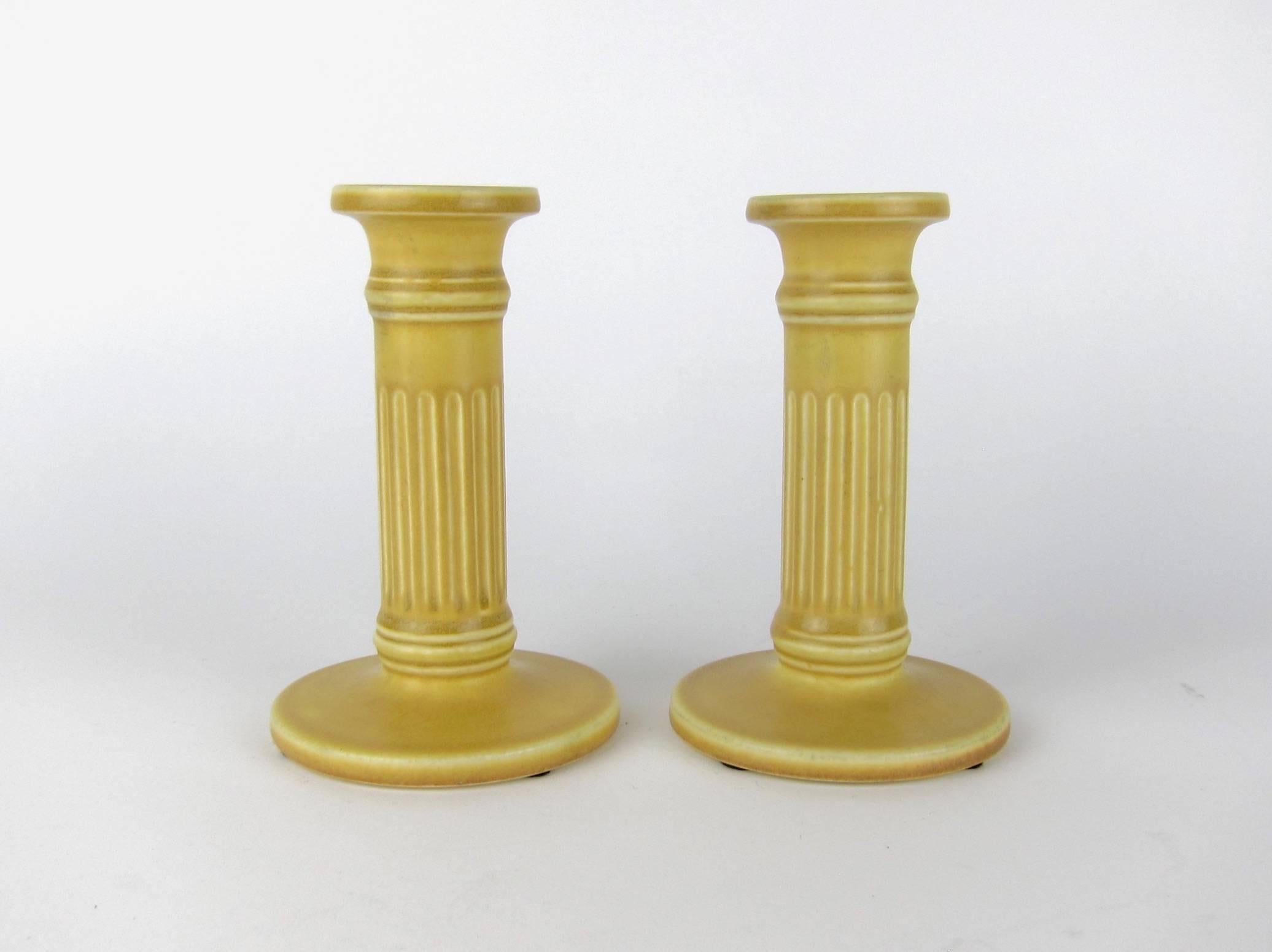 A pair of vintage Rookwood Pottery production candle holders made in 1923. The American Arts & Crafts candlesticks are shaped like fluted columns with a dark golden yellow matte glaze. 

Each in very good condition, measuring 5.75 in. H x 3.75 in.