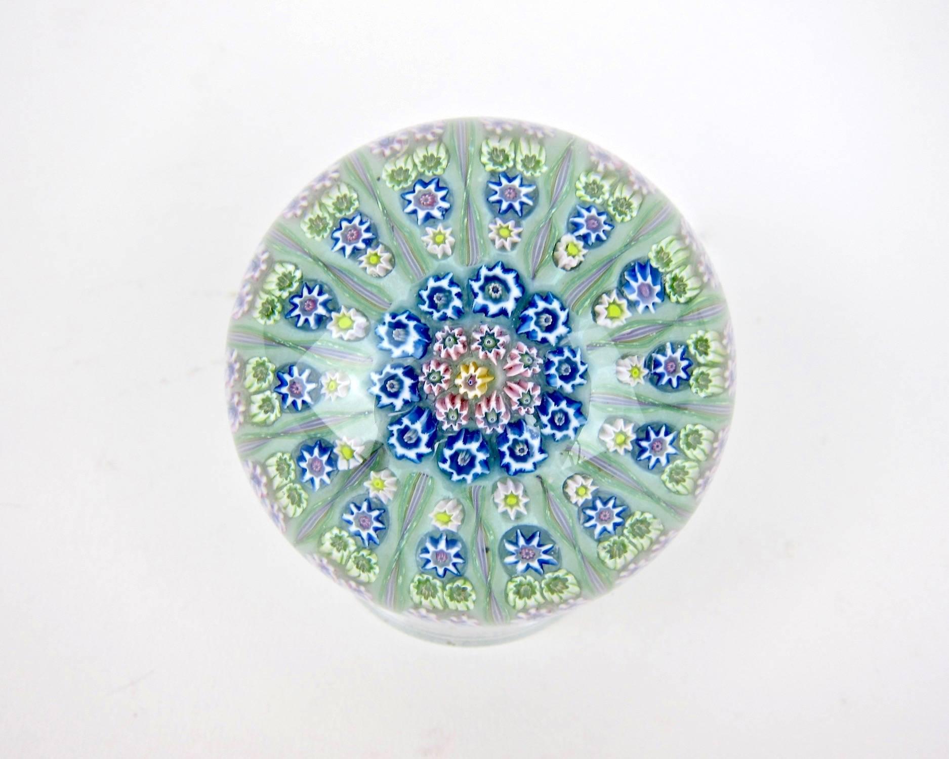 A vintage millefiori and twist art glass paperweight, handcrafted in Crieff, Scotland at Perthshire Paperweights, Ltd., circa 1969-1970.

Designed in a 1-1-2-2 pattern of fine millefiori canes separated by 14 spokes radiating from two rows of