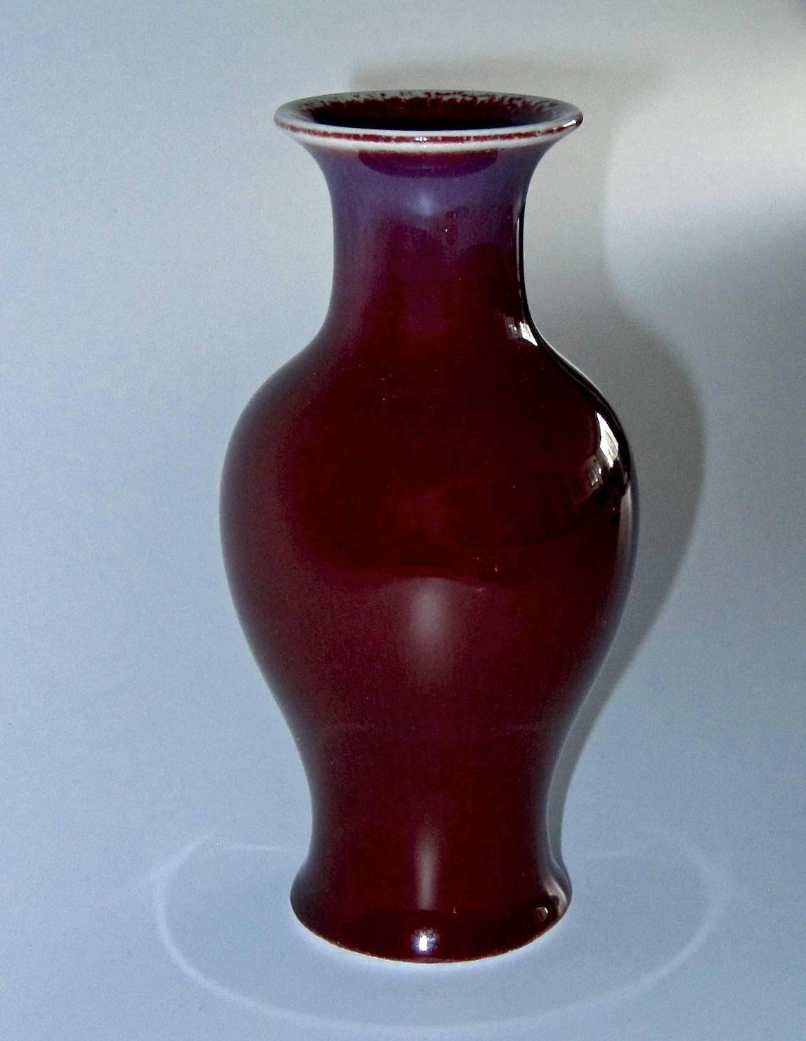 An antique Chinese vase manufactured circa 1880-1926 during the late Qing dynasty at Jingdezhen. The porcelain baluster form vase is decorated with a Sang de Boeuf / Oxblood flambé glaze with shades of blue / indigo around the neck. Excellent
