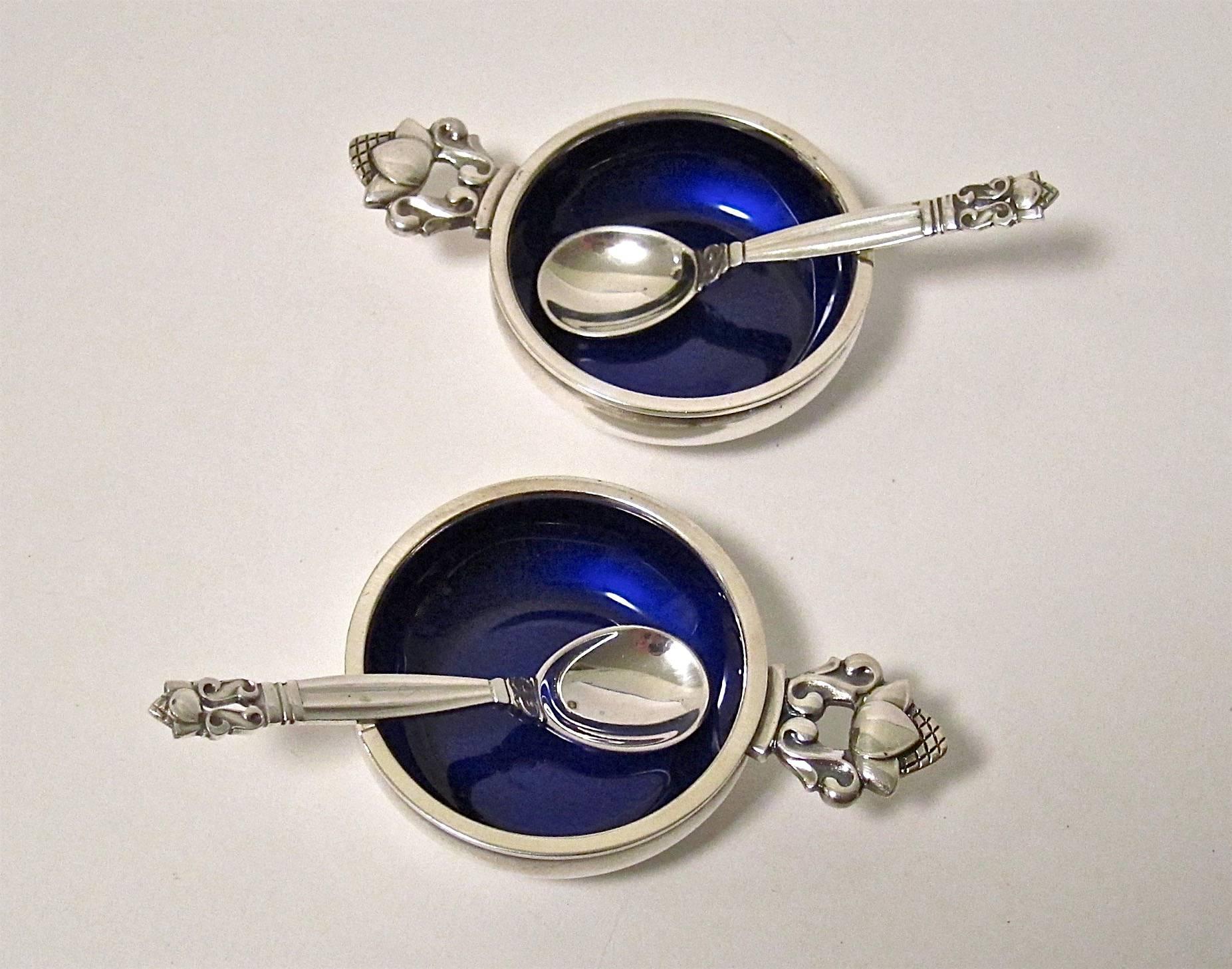 A vintage pair of open salt cellars with matching spoons in Georg Jensen's desirable acorn pattern, each bearing the JR cipher of Johan Rohde (1856-1945) who designed the timeless acorn pattern in 1915. 

Sterling silver with dark blue enameled