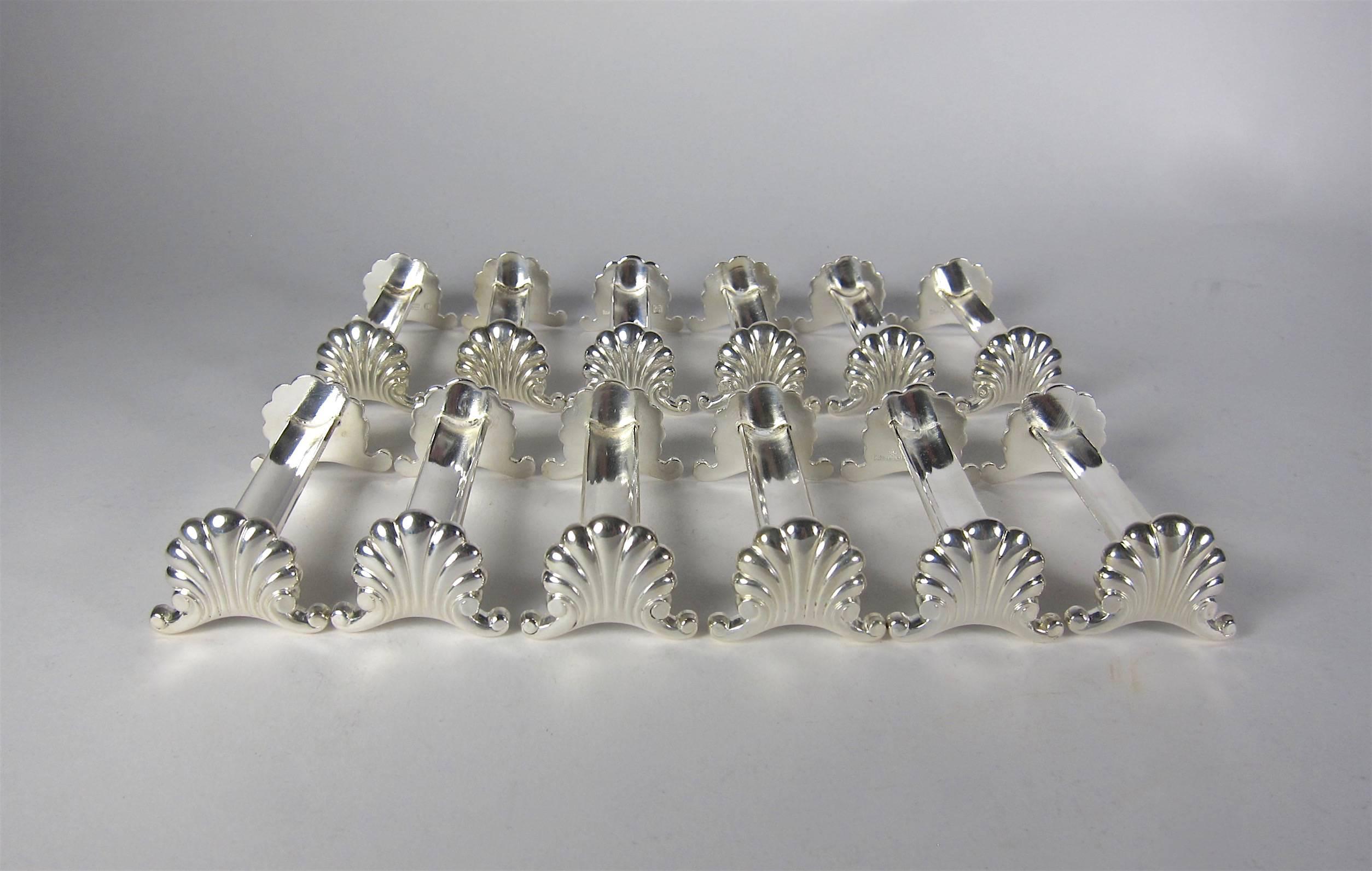 A set of 12 knife rests in heavy, high quality French métal argenté (silvered metal) from Ranivet d'Enfert of Paris complete with original fitted box. This early 20th century design features a simple Rococo style shell resting on flared C-scroll