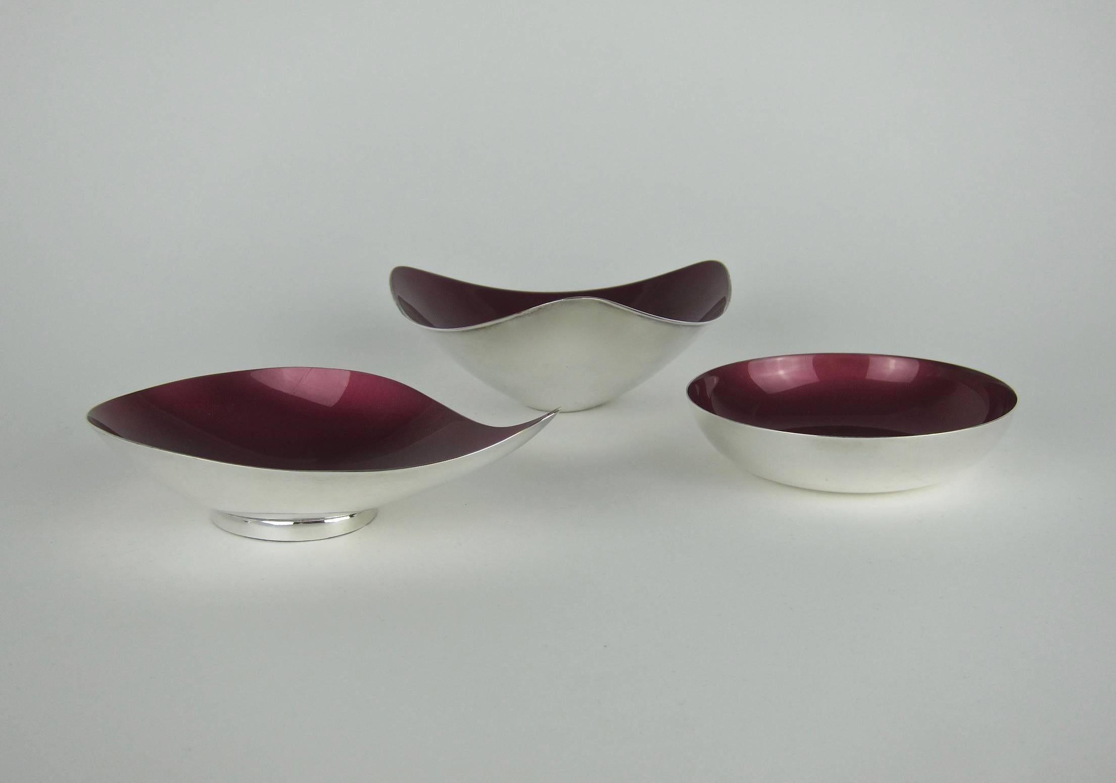 A set of three Mid-Century Modern bowls in a deep, ruby red 