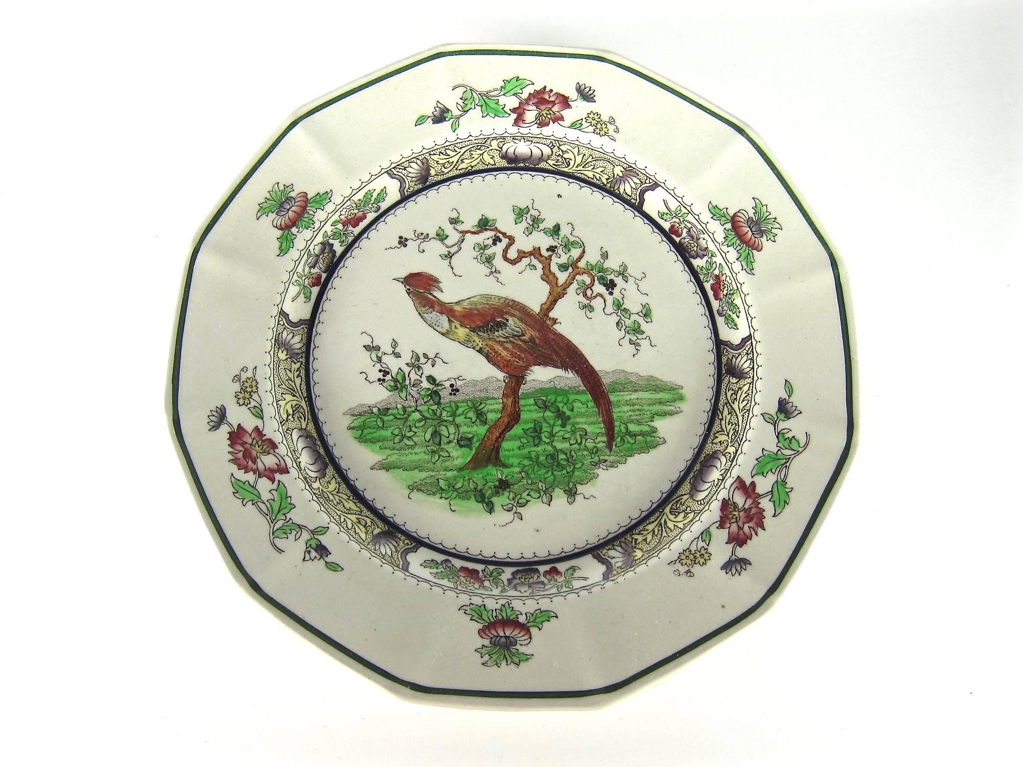 A colorful set of six antique Royal Doulton English plates with a hand-colored transfer-printed design of a pheasant perched on a Japanese Kakiemon-style tree, surrounded by leaves and blossoms with a dark green line bordering each rim. Royal
