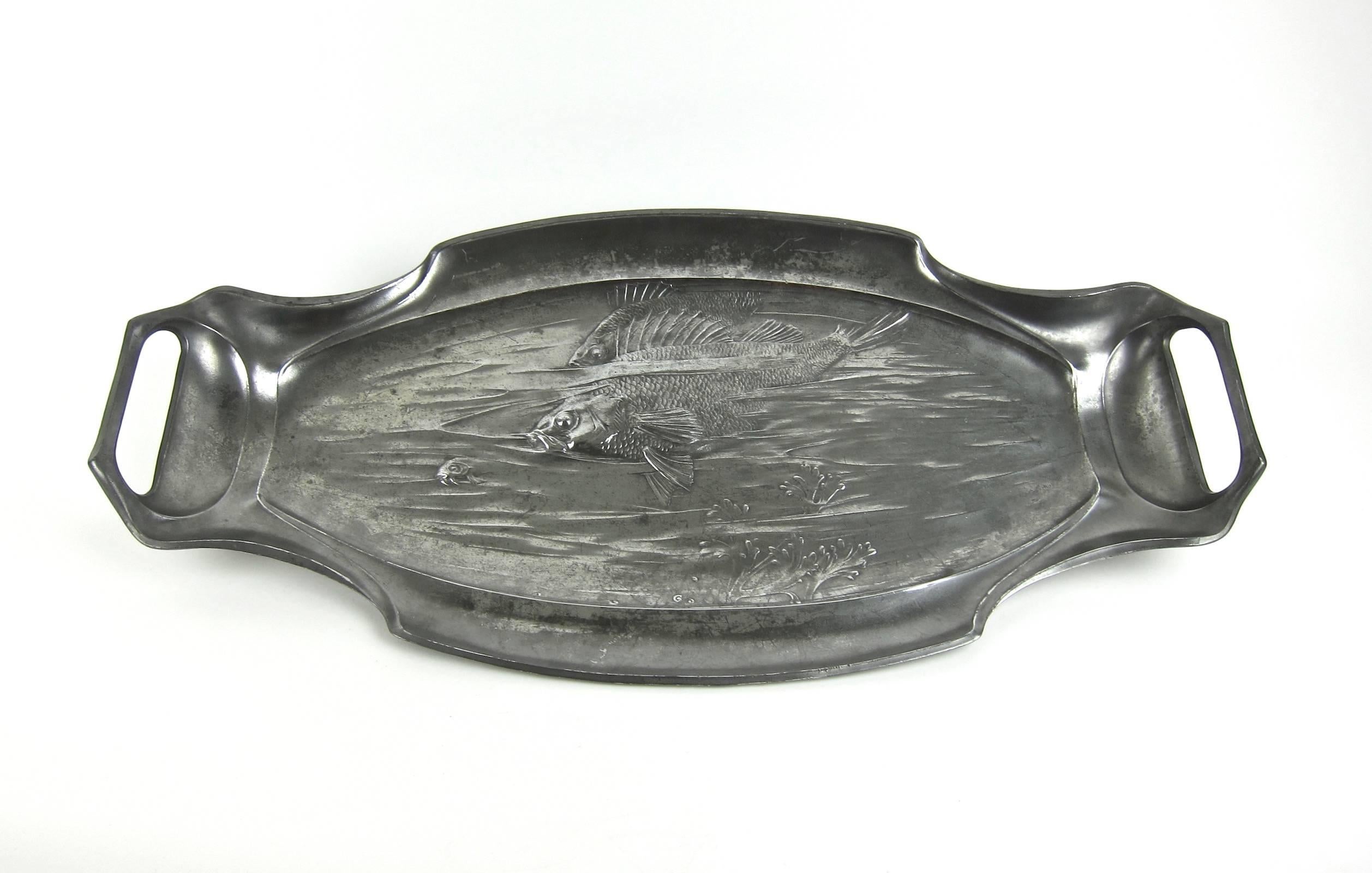 An extraordinarily large and heavy two-handled antique pewter platter produced by Orivit-AG of Germany, circa 1900. The Jugendstil decoration consists of an underwater scene in relief depicting three Art Nouveau fish swimming across the silvery-gray