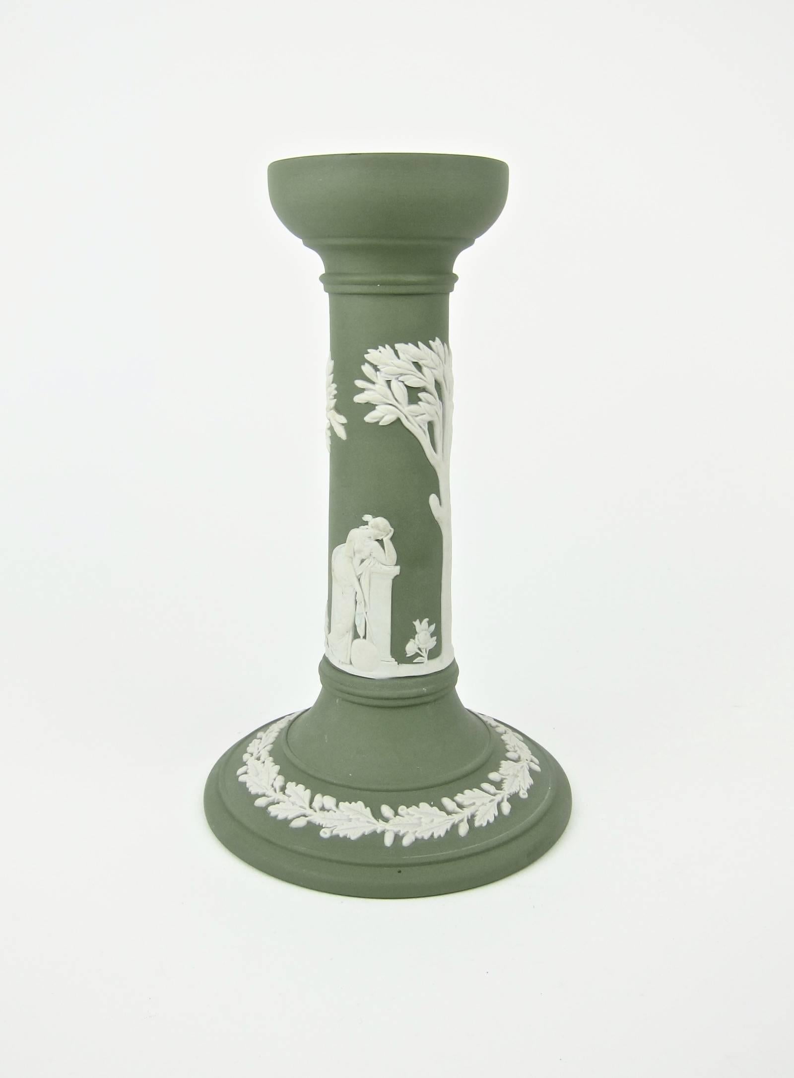 A pair of vintage pillar candlesticks from an important California collection of English Jasperware by Wedgwood. Each candle holder has a green body of solid jasper sprigged with Neoclassical figures and trees with a band of oak leaves and acorns