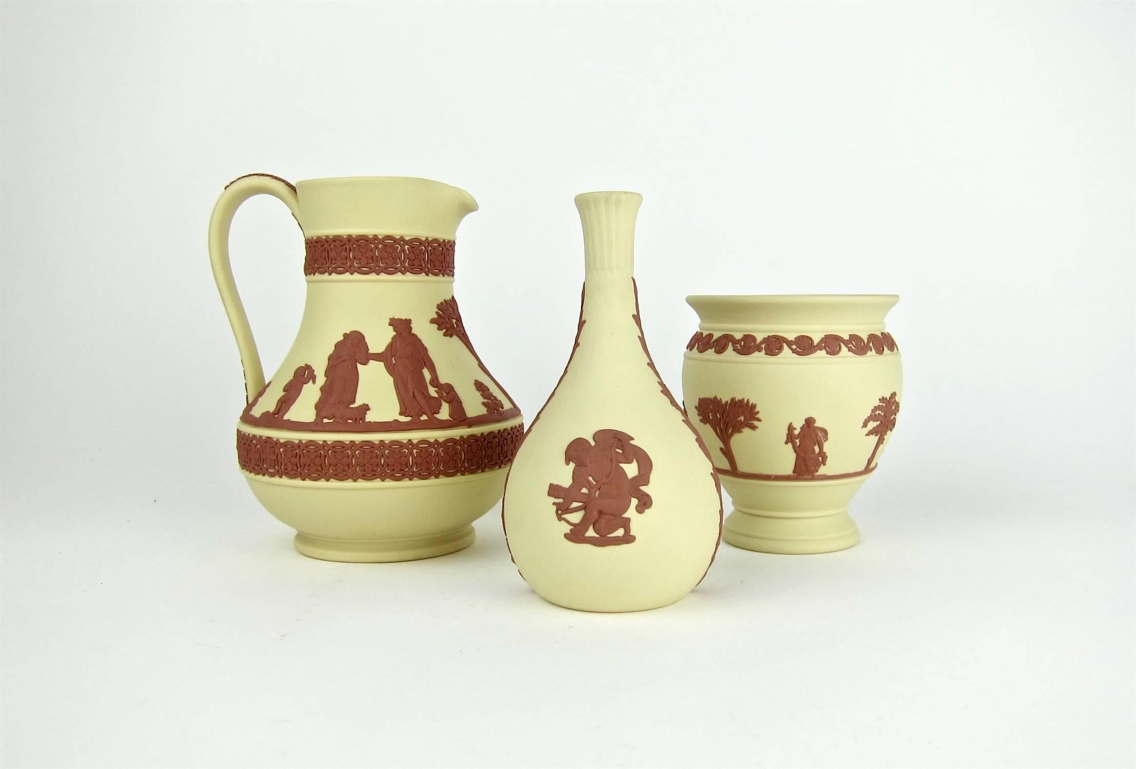 A striking vintage collection of three Wedgwood vessels in an unusual combination of Terra Cotta on solid Primrose Jasper ware. The set consists of a Potpourri vase or posy pot, a Cherub bud vase, and an Etruscan jug, decorated in the neoclassical