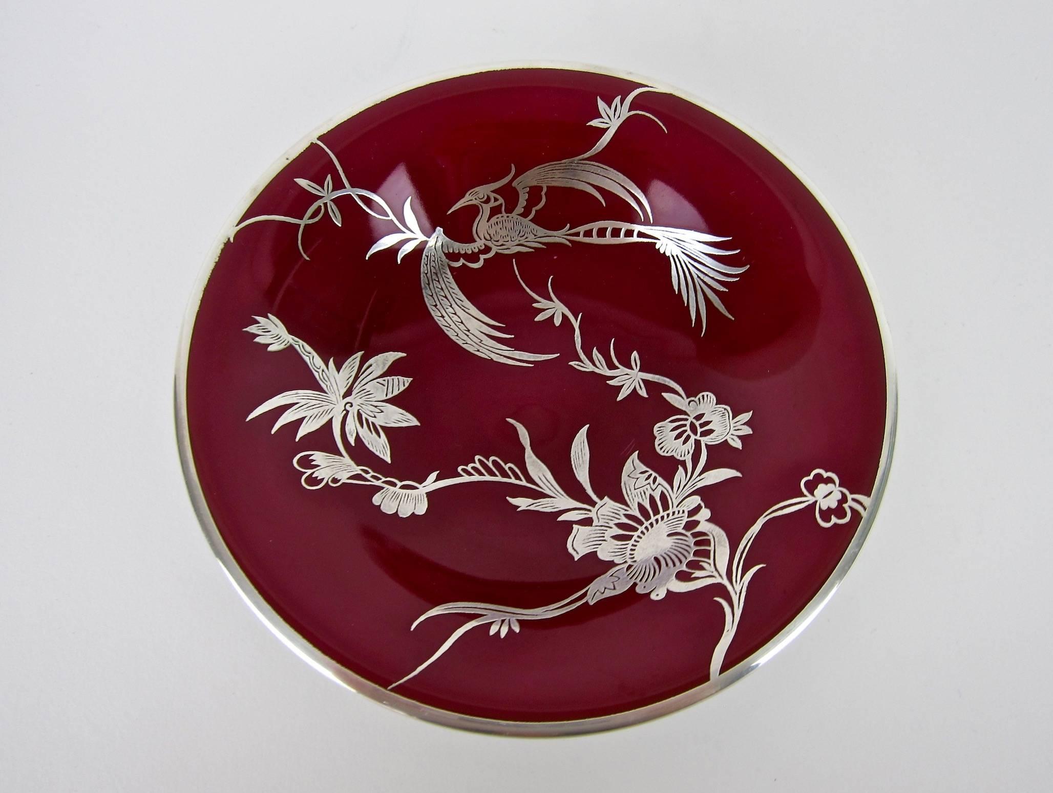 An exquisite Rosenthal porcelain footed bowl ornamented with an elegant, pure silver overlay design handcrafted in Germany between 1953 and 1956. The silver overlay work features a Chinoiserie-style Bird of Paradise motif with two silver bands at