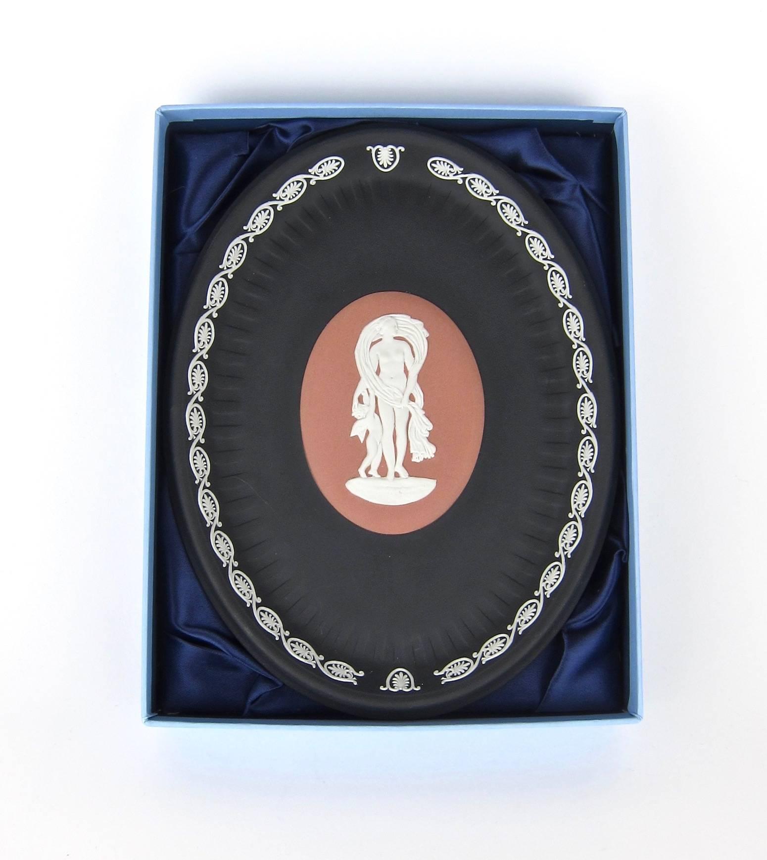 A handsome 'Venus and Cupid' oval tray with a satin lined and fitted box, signed by Lord Wedgwood in 2002. The tray is decorated in the Classical style with white bas relief jasper figures on an oval terra cotta central medallion, surrounded by