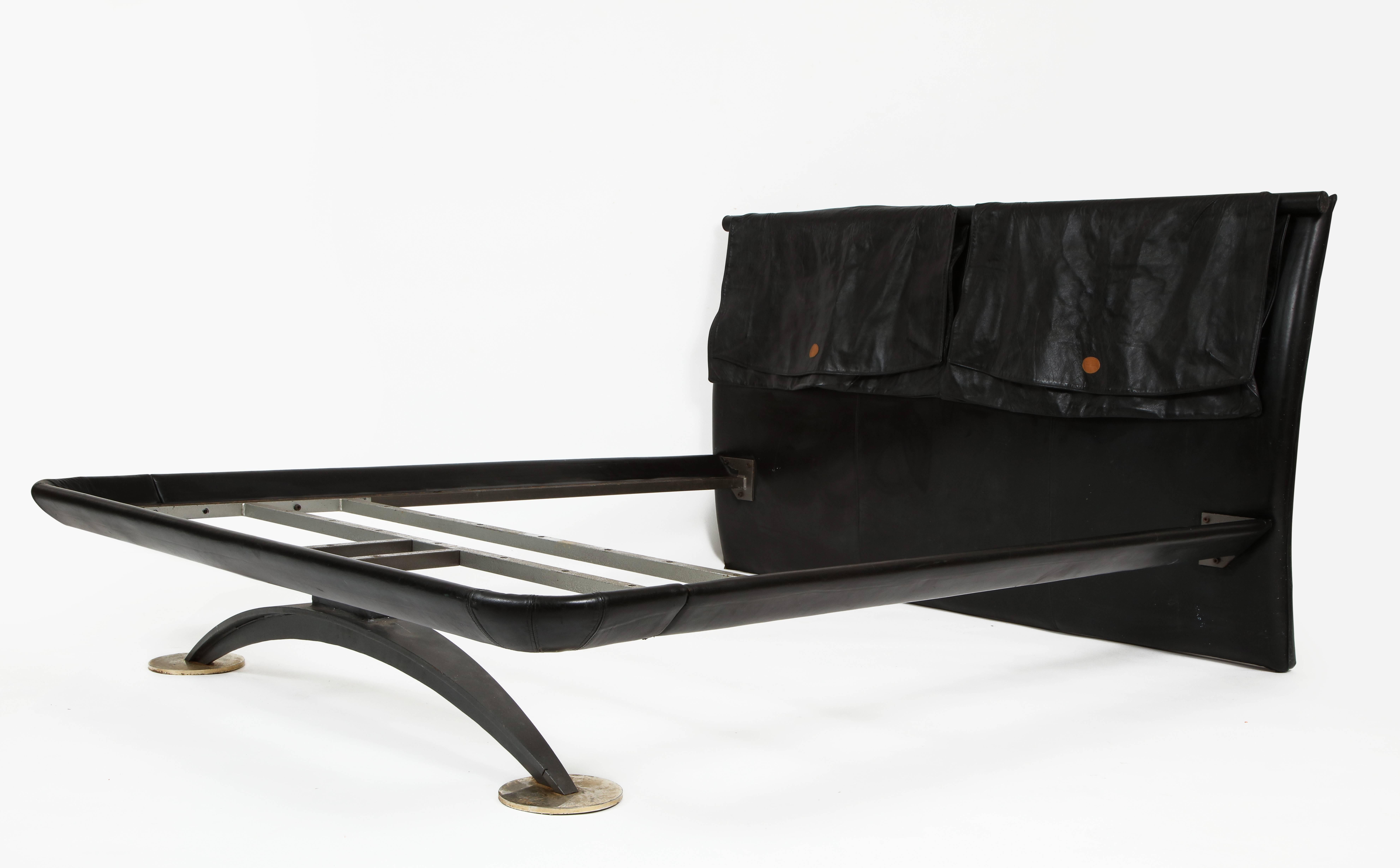 Pierre Cardin black leather bed bronze and iron base, 1970s-1980s. 

Rare and chic black leather and faux leather bed made by Pierre Cardin.
The headboard is faux leather, and there are two large leather pieces that wrap over the headboard that hold