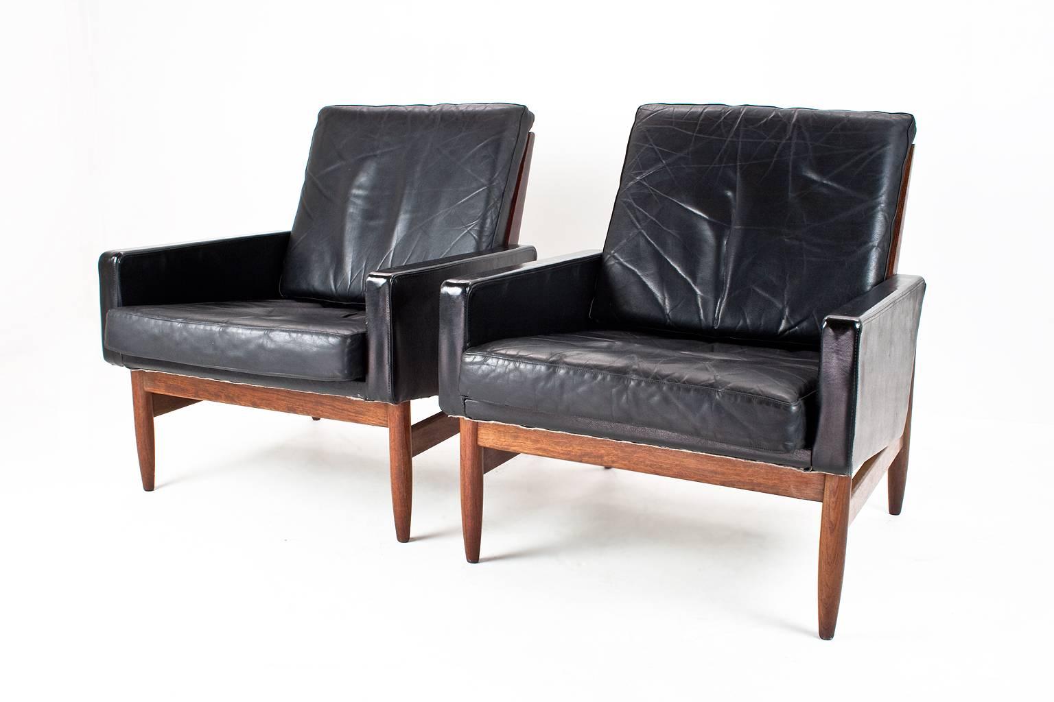 Pair of Scandinavian Mid-Century lounge chairs on a teak frame with rosewood shell and black leather upholstery in original yet very good condition. The seat cushions have been filled with new foam. 

These chairs are a great example of the