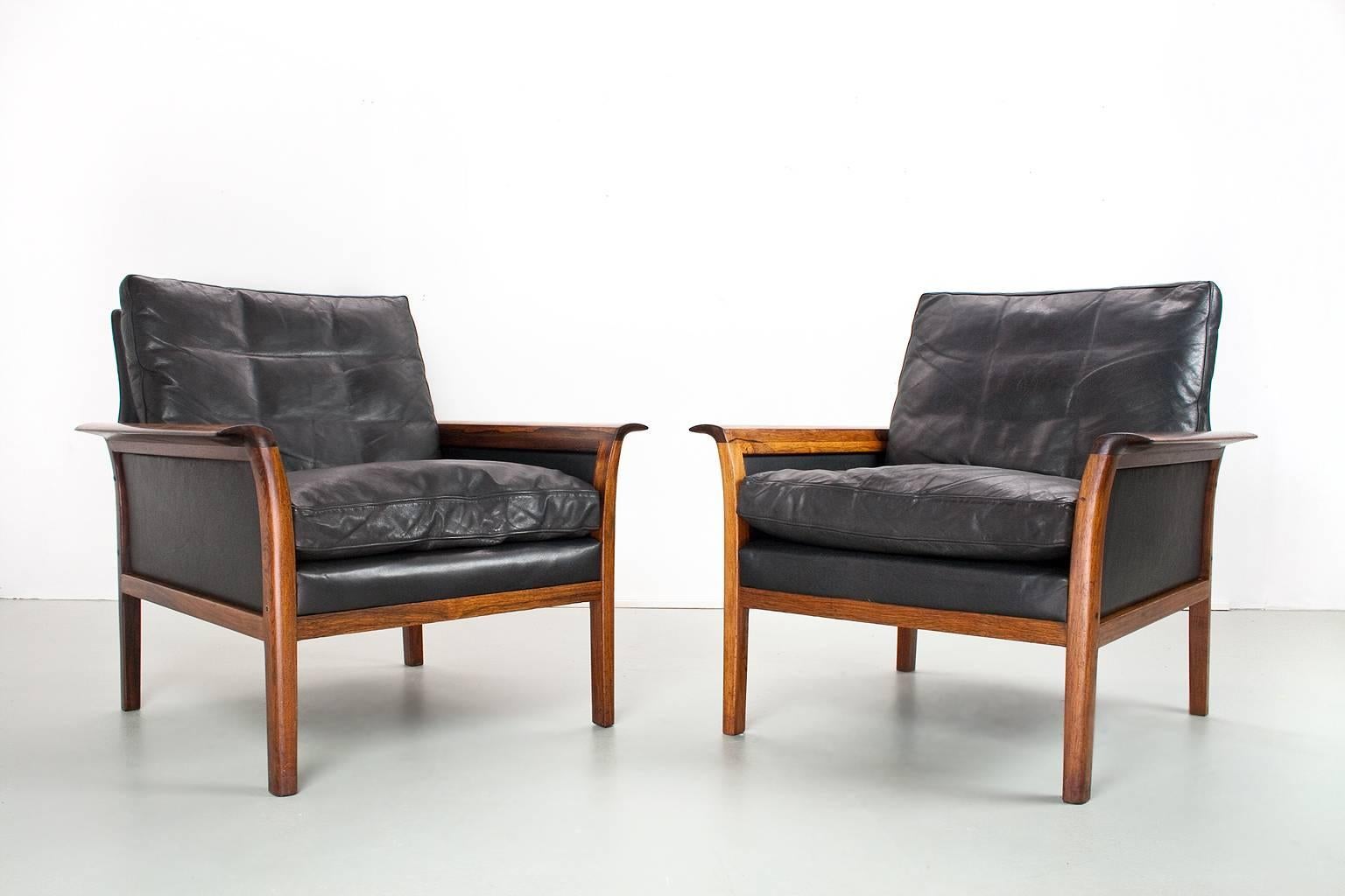 Pair of Scandinavian midcentury lounge chairs with rich vintage black leather and sculpted armrests on a well-constructed rosewood frame, in original yet very good condition by Knut Saeter for Vatne Mobler. The seat cushions are filled with