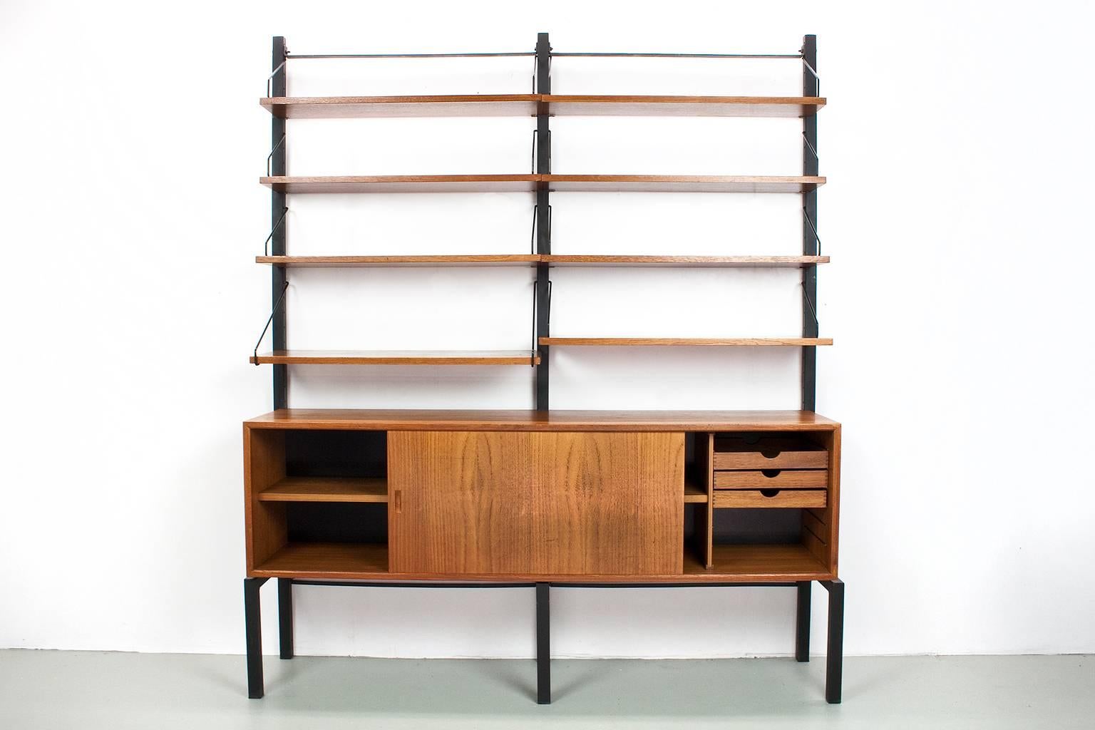 Original freestanding wall unit designed by Poul Cadovius, model Royal, in the 1950s for Cado, Denmark. This listed unit was produced by Cado in Denmark in the 1960s. The elements features a lovely quality teak veneer with black metal uprights of