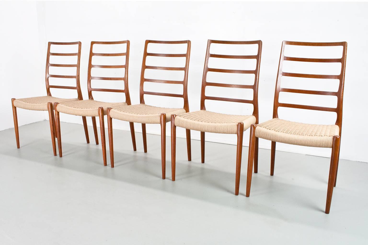 A great Scandinavian modern set of 5 dining room chairs. This organically shaped chair with the high back (model 82) was designed in 1954 by Niels O. Moller for J.L. Møller Møbelfabrik. The items have been completely restored with new paper cord.