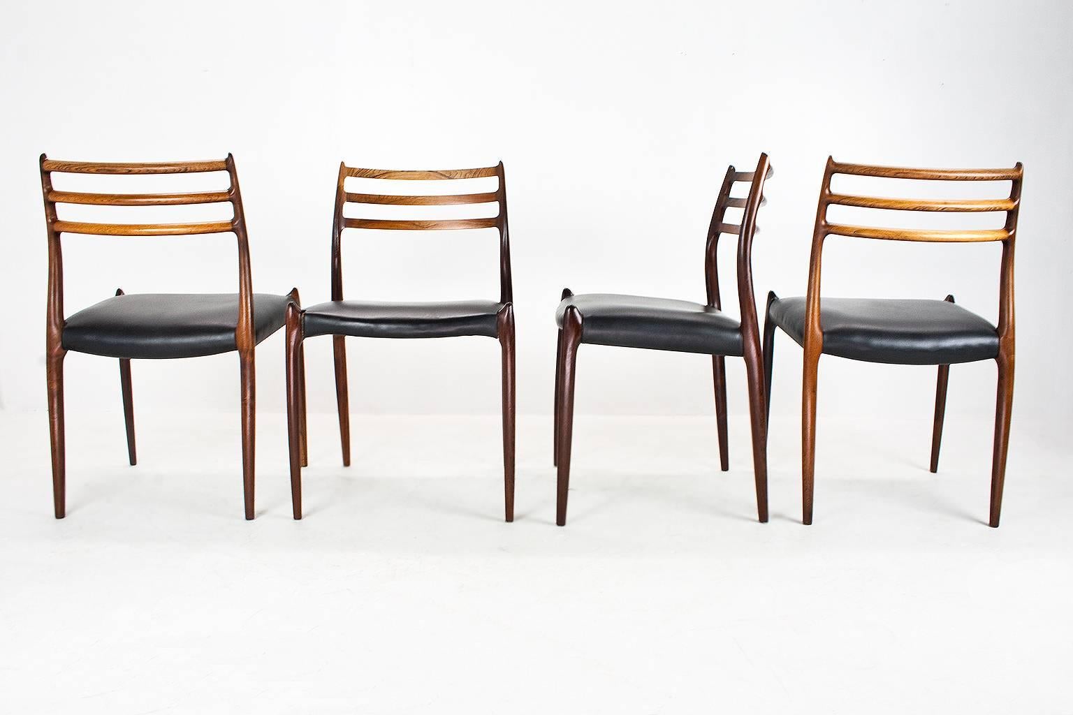 Set of four organically shaped dining chairs in rosewood and black faux leather, model 78, designed in 1954 by Niels O. Moller for J.L. Møller Møbelfabrik. The chairs are marked with the manufacturers plates and stamps below the seating.

The chairs