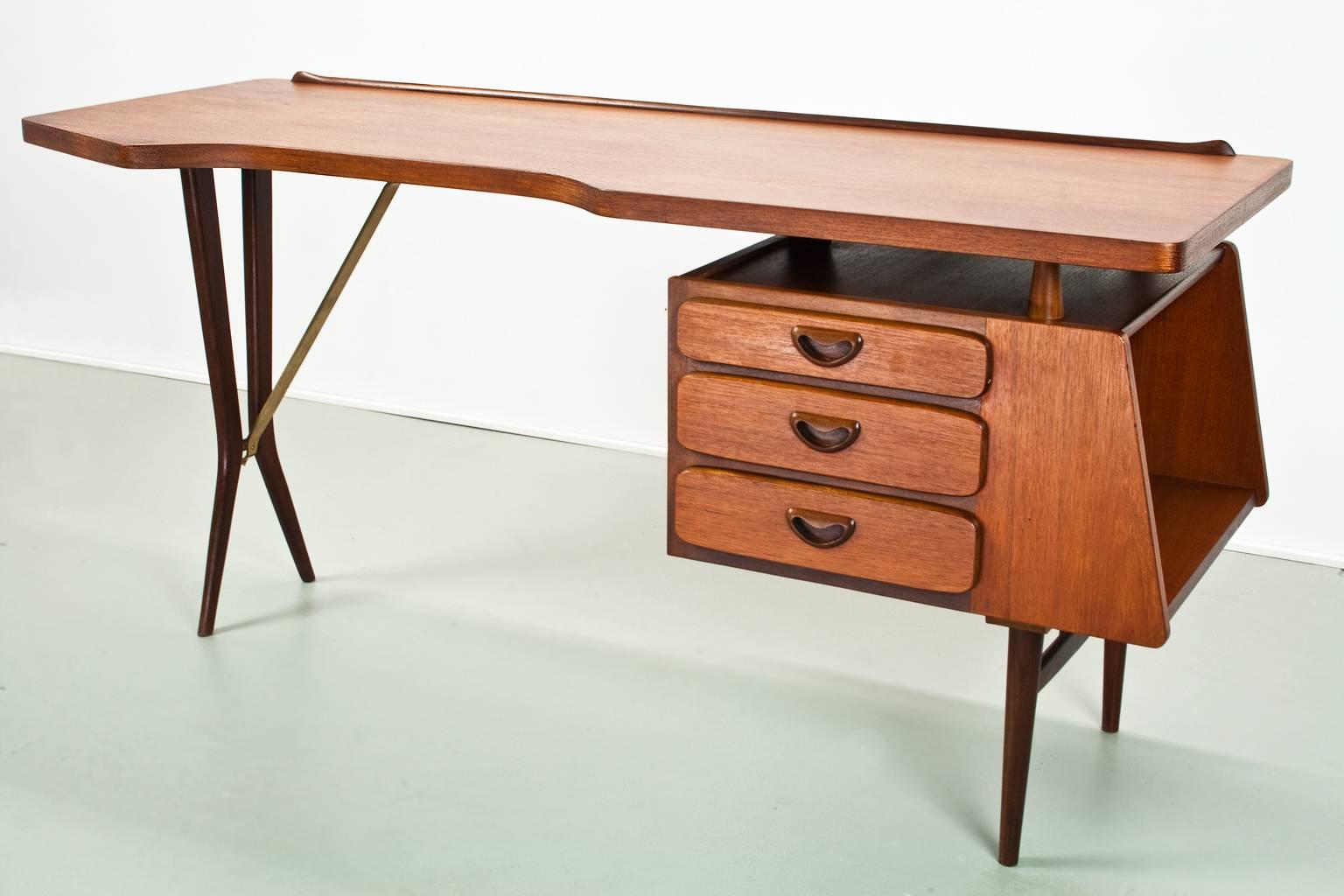 Original and fully restored iconic Mid-Century Modern desk with floating tabletop and brass detailed arm on the black lacquered wooden legs. In absolutely excellent condition. 
Writers desk designed by Louis Van Teeffelen in the 1950s for WéBé