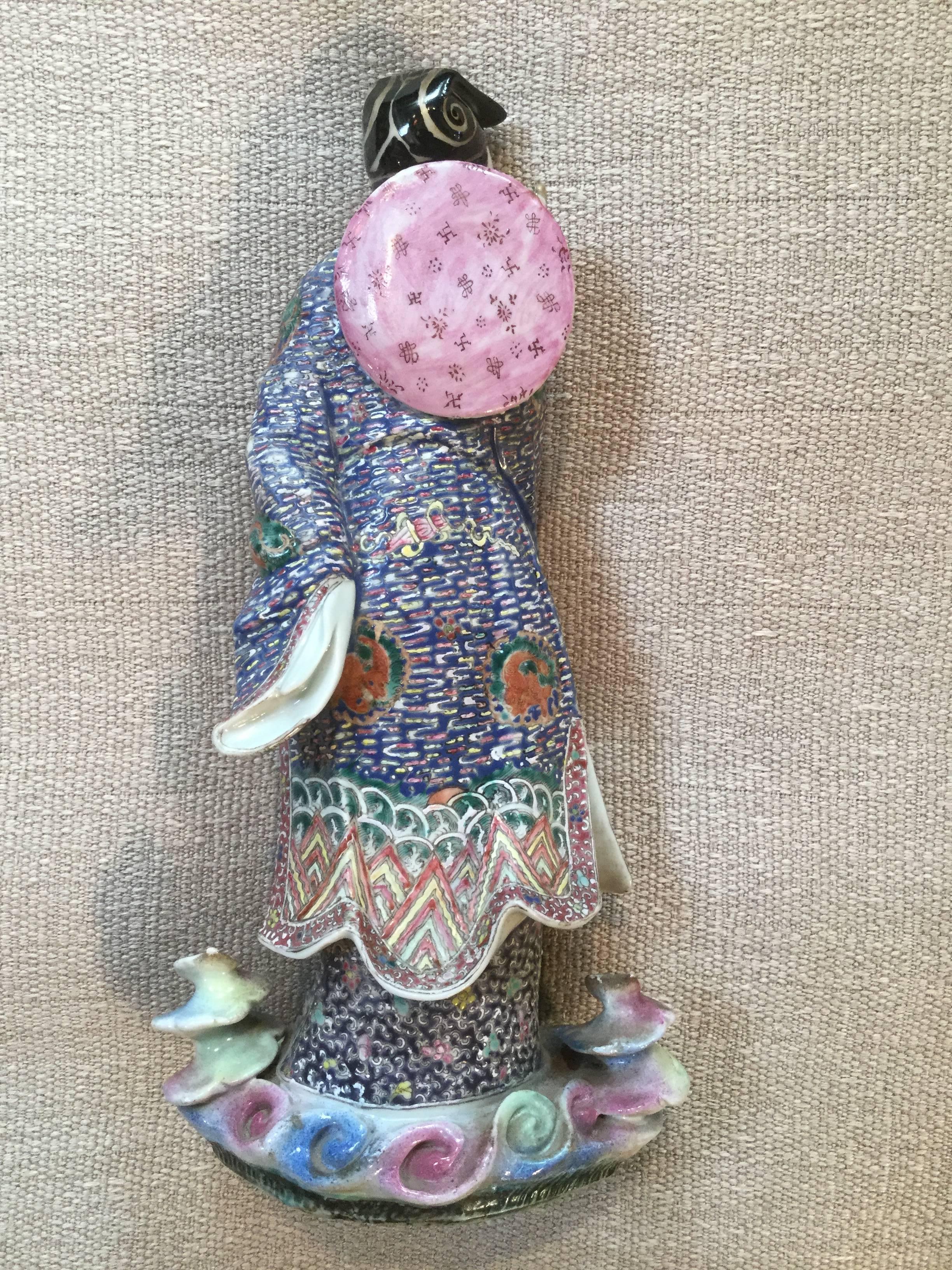 This is a fine, Famille Rose standing porcelain figurine of a bearded sage holding a whisk. Draped in elaborately and minutely detailed robes, he is standing upon a cloud swirl base. His robe displays the happy ornaments in enamels of pink, blue,