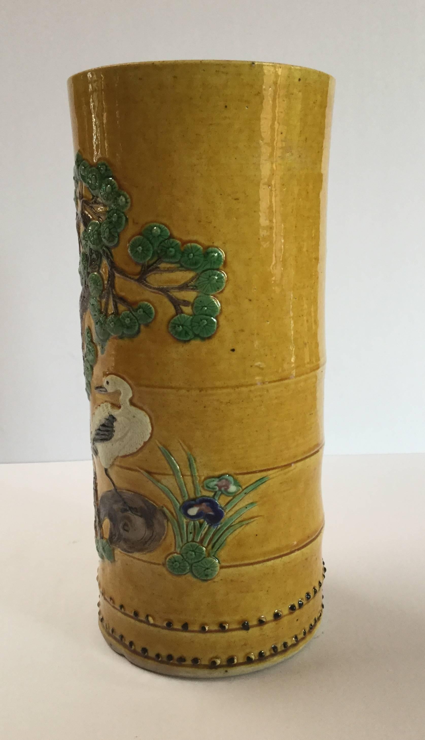 A beautiful cylindrical shaped ceramic arrow vase of ochre yellow with green, white and brown glazes depicting a twisted pine tree, spotted deer and cranes. This piece is from a private collection in Santa Fe, NM.