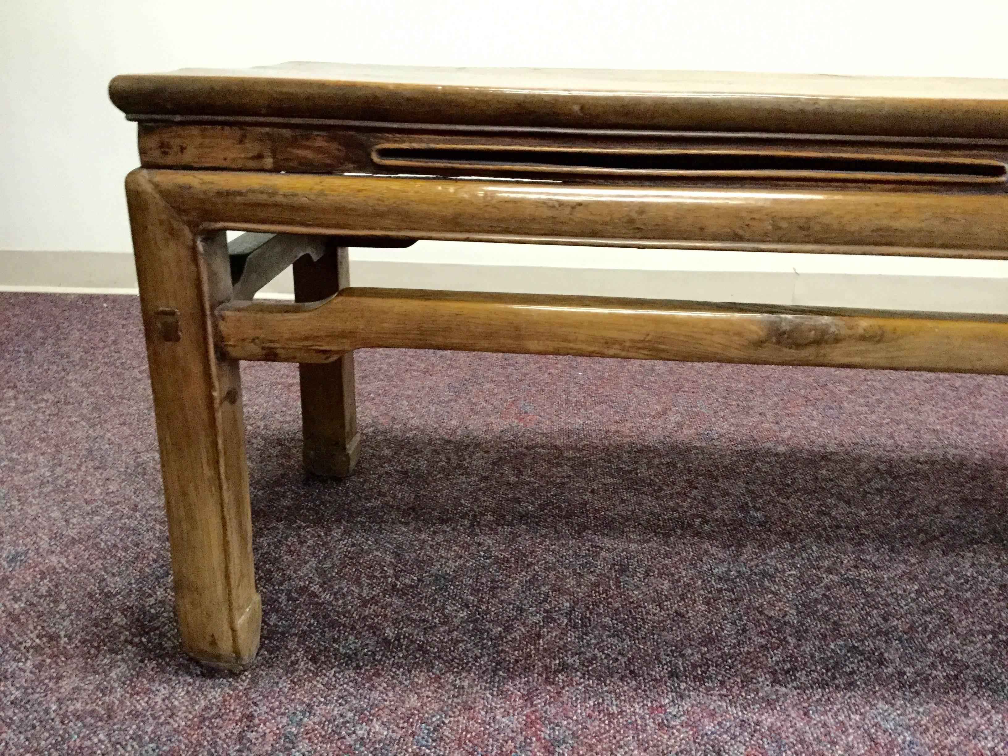 Graceful lines, typical of the Ming dynasty are evident in this simple bench. The horseshoe feet and support bar exemplify the style.
Crafted of hand hewn elmwood and with faded lacquer in rich deep red, in a band around the top of the bench.
 