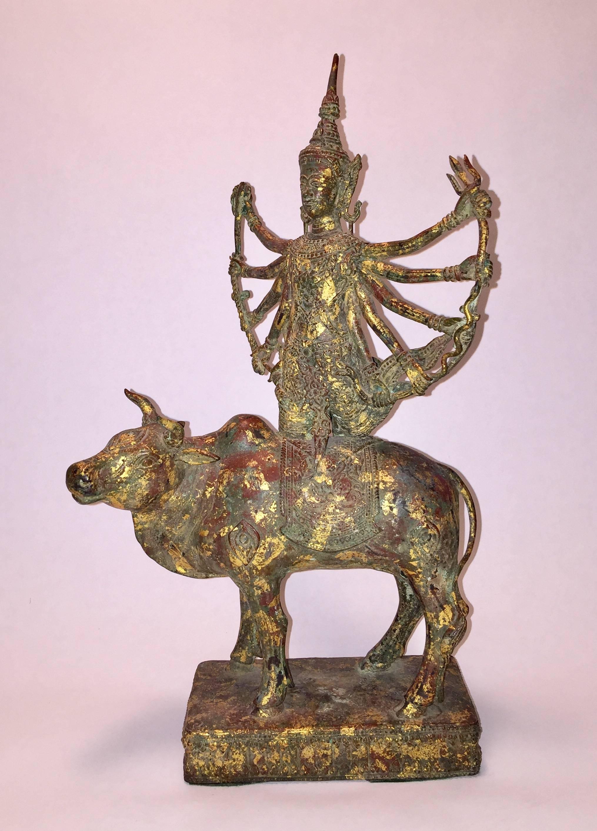 This rare statue depicts the Goddess Durga seated on a bull. Adorned with gold leaf flakes.