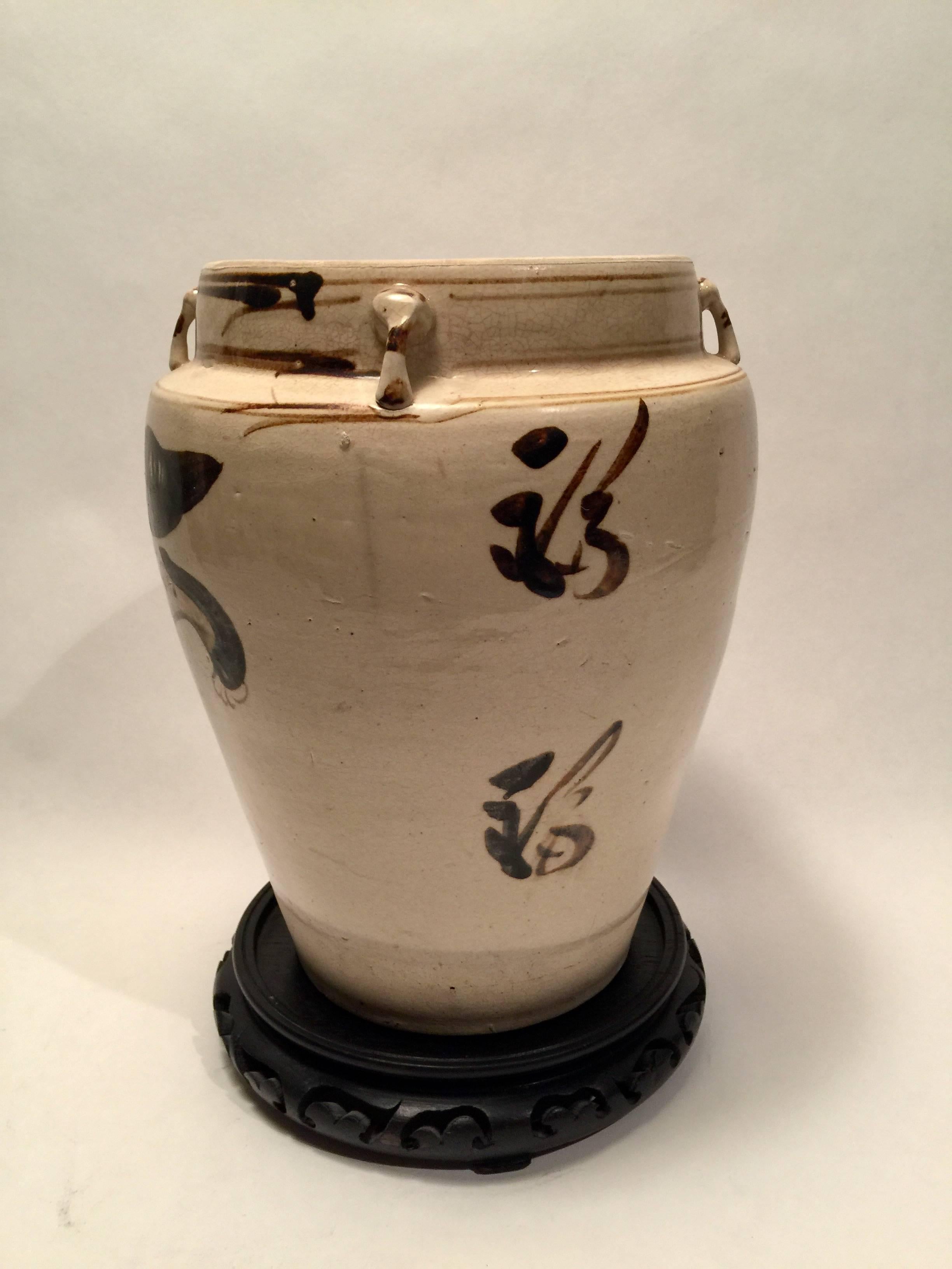 The ovoid body of the vase is glazed with a translucent cream crackle and features a boldly painted Kylin (lion) in chocolate brown glaze. Loop handles are applied to the neck. Late Yuan or early Ming dynasty.
