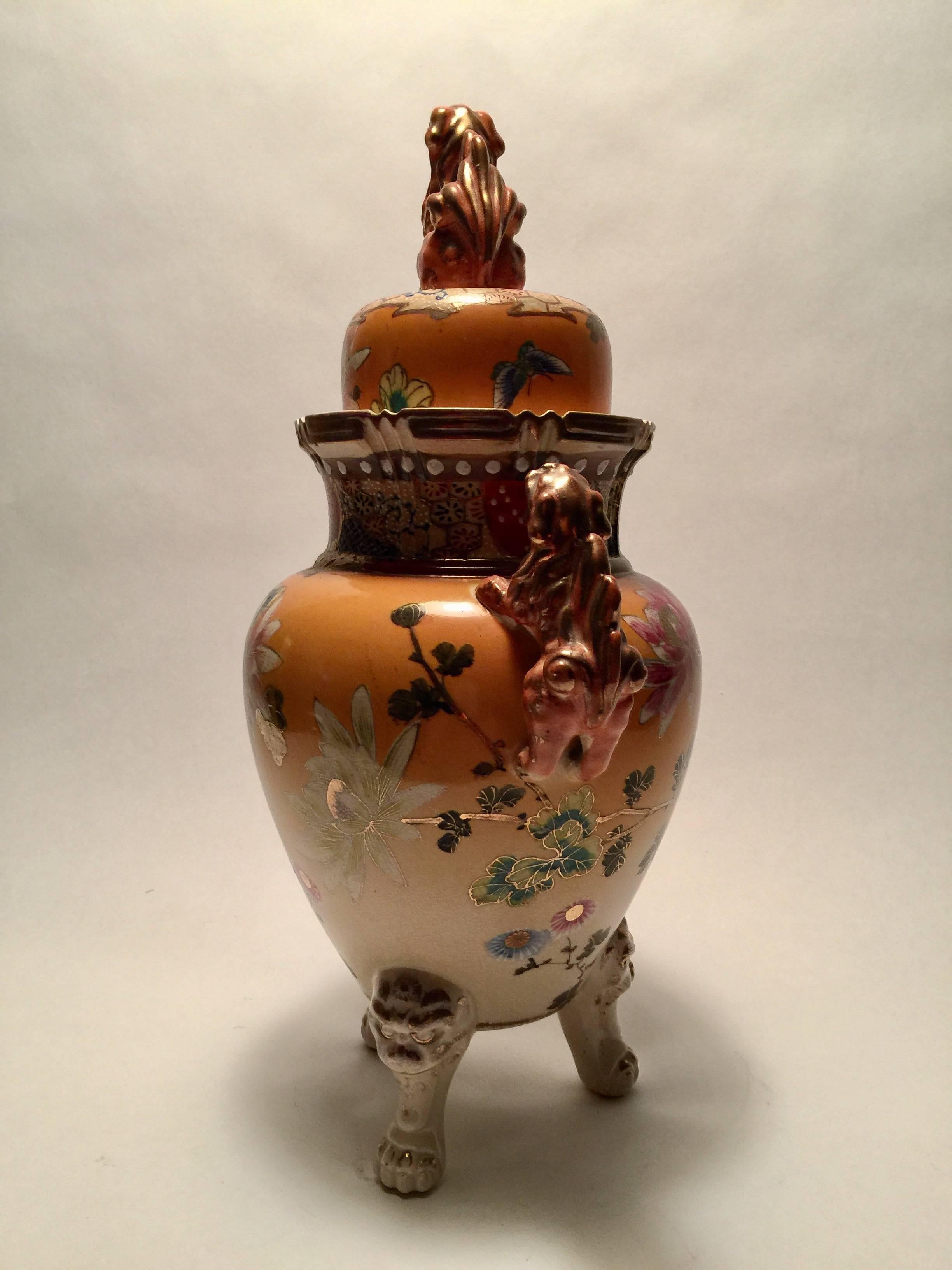 Typical of Early Satsuma pottery, usually hand-painted by women, this three legged censor is beautifully decorated with asymmetrical flowers. The ombre shading done in a fantastic yellow orange color serves to set off the flowers painted in fuchsia