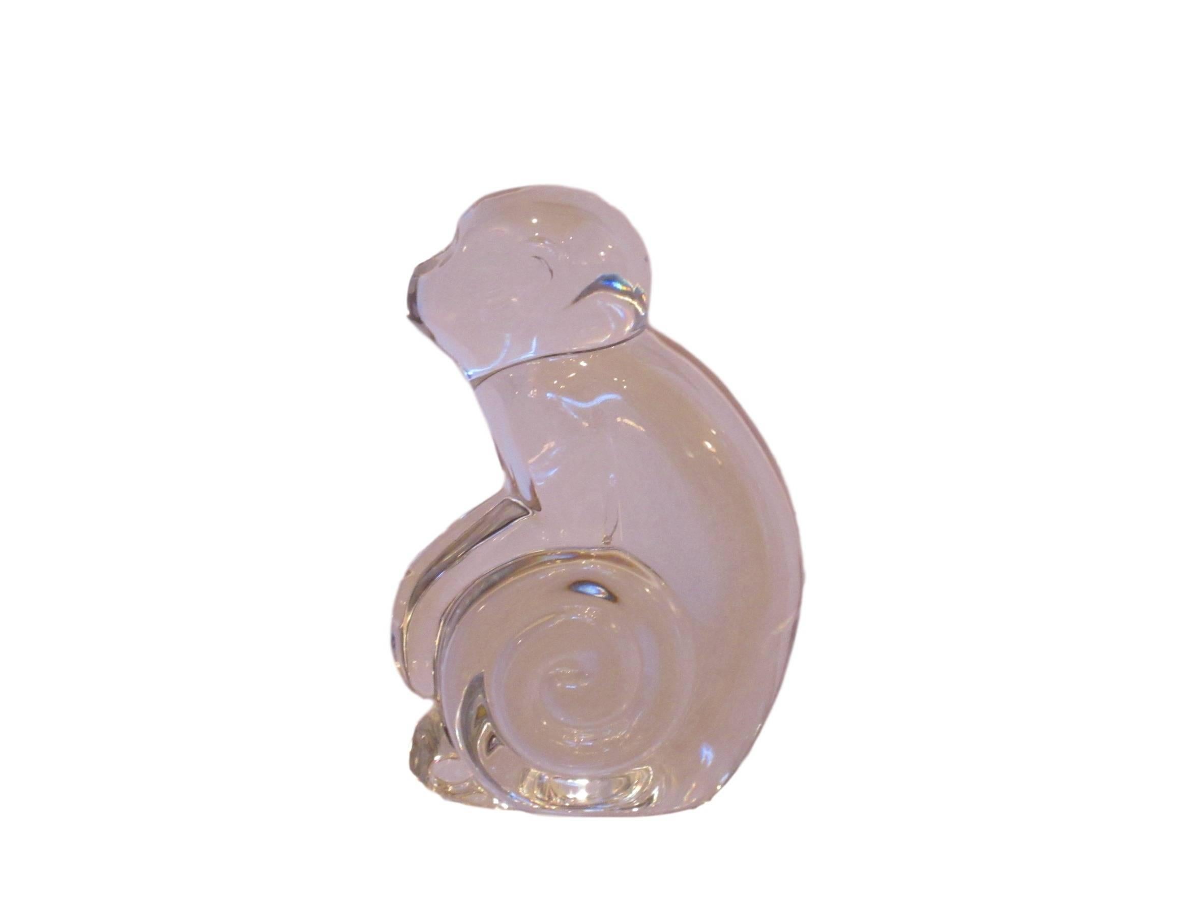 A crystal monkey sitting with his tail curled like a spiral under his arms. Signed De Sousa on the bottom. A great stylized piece for decoration or a paperweight. marked “Val St.”.