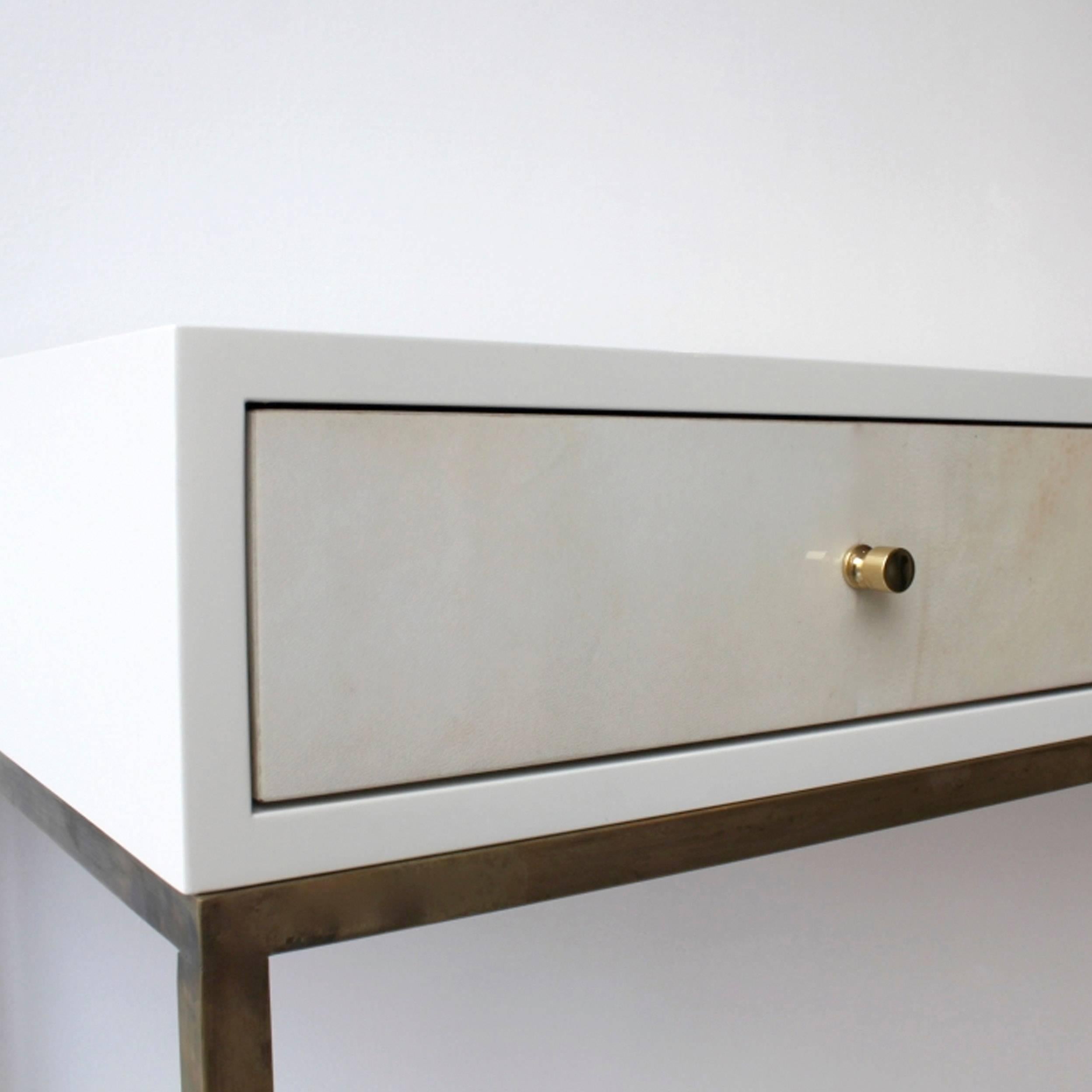 White (RAL 9001) piano lacquered desk with brass lined drawers, antique brass frame base, vellum parchment front drawer detail and brass pull knobs. Also available in black (RAL 9004) piano lacquered colour finish outer frame. Bespoke dimensions and