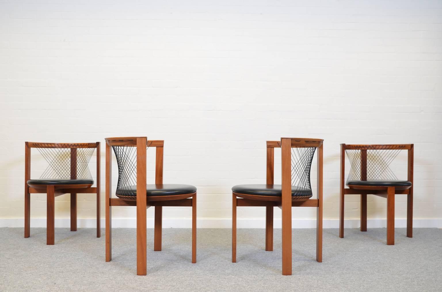 Set of four dining chairs by Niels Jørgen Haugesen for Tranekaer. The chairs have a mahogany base and black leather seats. Backs with black nylon cords. The chairs are all in a very good condition.