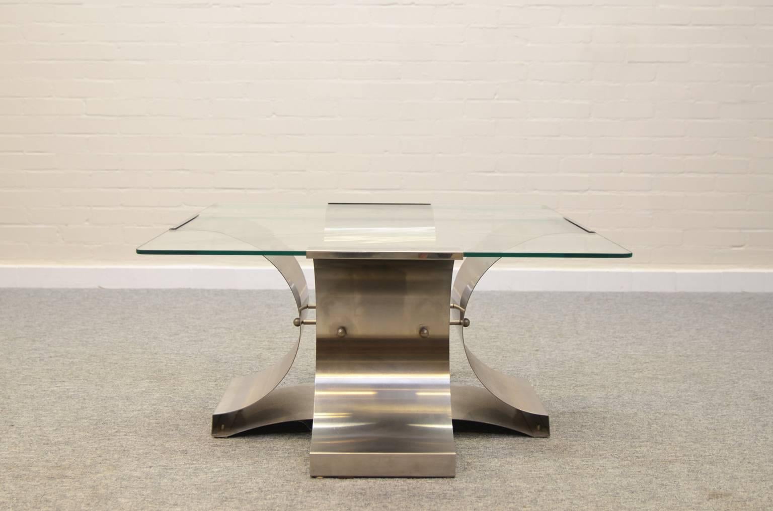 Coffee table from the 1970s by François Monnet. The table has a unique shaped base made of stainless steel. The glass top (8mm) ensures a good look at the base. The table is in a very good condition; glass with small scratches and tiny chips, some