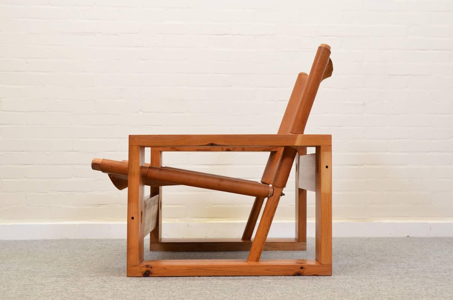 Very robust armchair made of pine wood. The seating and backrest are made of saddle leather and are suspended in an ingenious fashion in the frame.