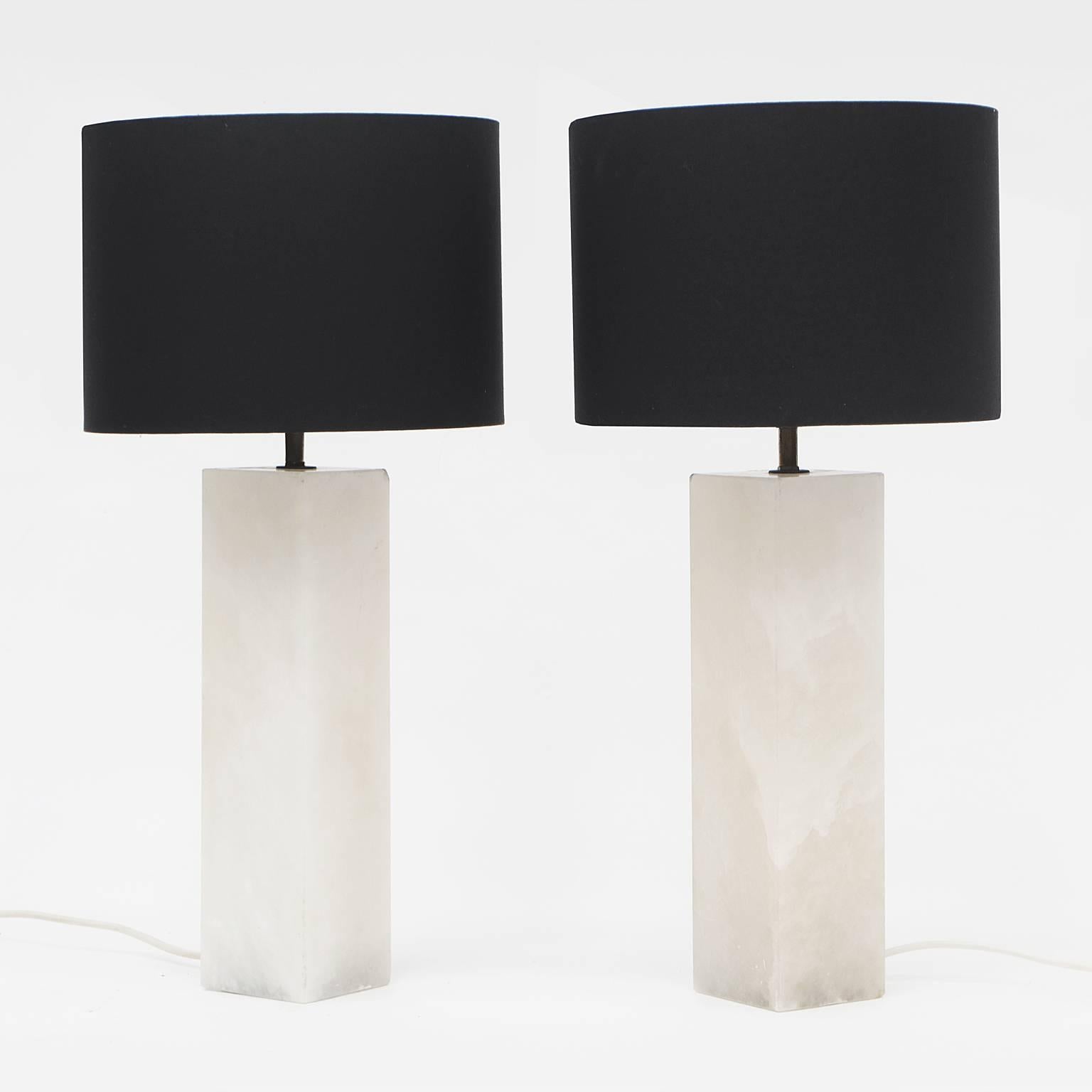 Pair of white onyx table lamps designed and manufactured in Italy.

White onyx column bases with brass fittings. Black drum shades.

With shade: H 58cm x D 28cm
Without shade: H 45cm x D 9cm

Each lamp weighs an impressive 8 kilos each.