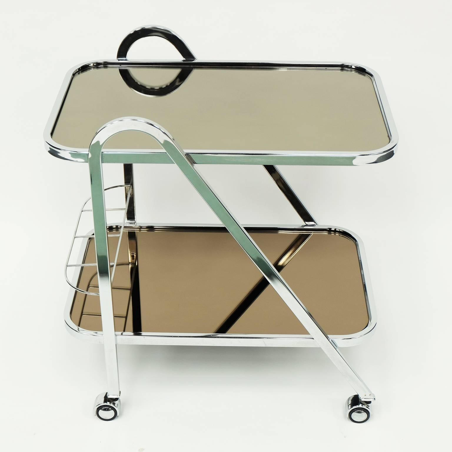 1970s cocktail cart designed and manufactured by Milo Baughman, USA.

Chrome frame with two tinted mirrored glass shelves and bottle rack.

Chrome castors.

Measures: H 75cm x W 70cm x W 48cm.