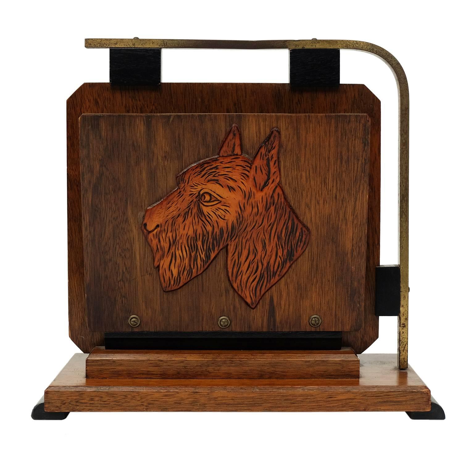 1940s magazine rack designed and manufactured in Belgium. 

Stained oak form with detailed wooden reliefs depicting two different terrier dogs.

Brass handle and ebonised feet.

H 33cm x W 34cm x D 15cm.