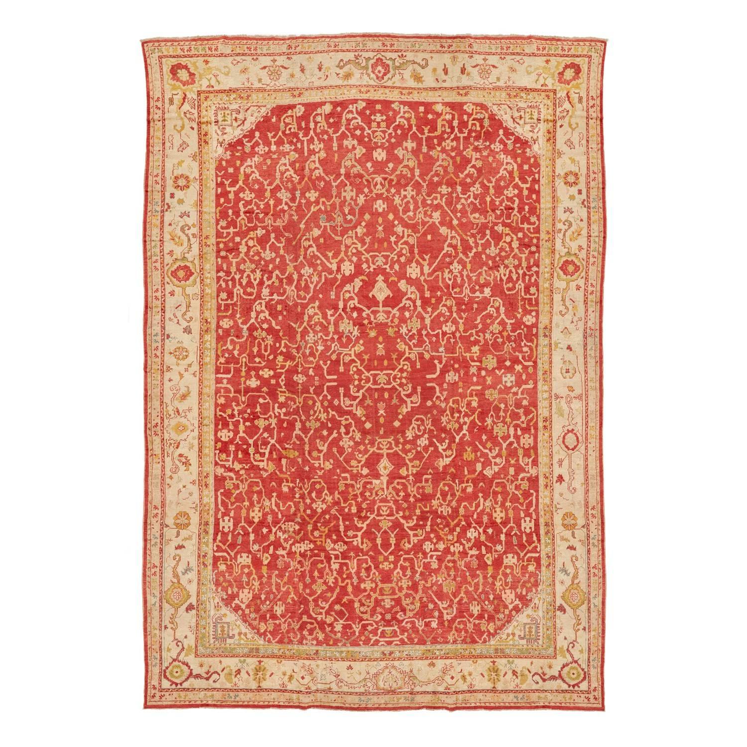 This massive antique Oushak wool rug, handwoven in Turkey, features an all-over pattern of vines in a rich, saturated palette. Vivid madder and saffron hues highlight the traditional patterns. Renowned for their distinctive composition and use of