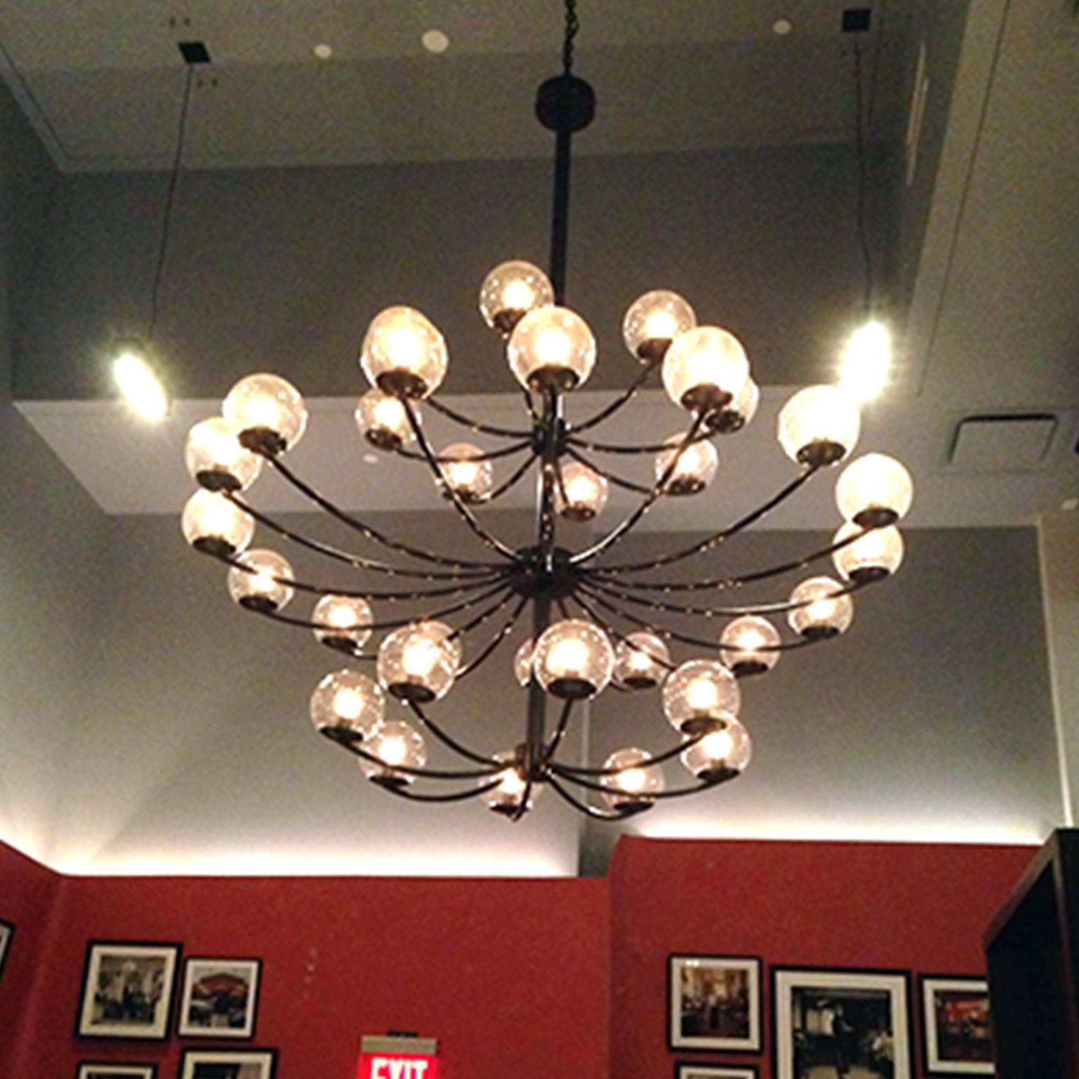 1940s chandelier - hand crafted in our Tribeca studio and showroom. 
Metal / brass / burnt steel / finishes.
Blackened.
Metalwork.
Welded
Glass.

Measures: 52″ W x 54″ H.
Approximate lead time 11-12 weeks.
Additional custom sizes and finishes