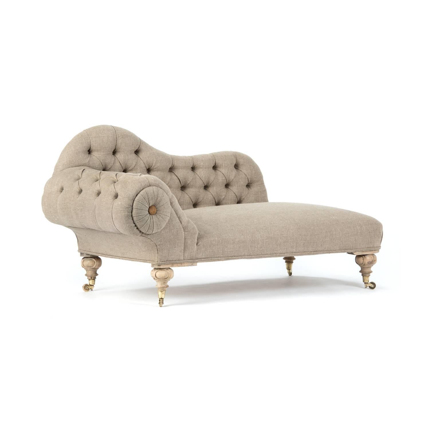 Unusual Victorian scroll arm deep buttoned tufted chaise longue reupholstered in a natural organic flax linen with padded arched back and piped detail, capped with an oversized whirl and suede button.

Bleached and waxed legs resting on original