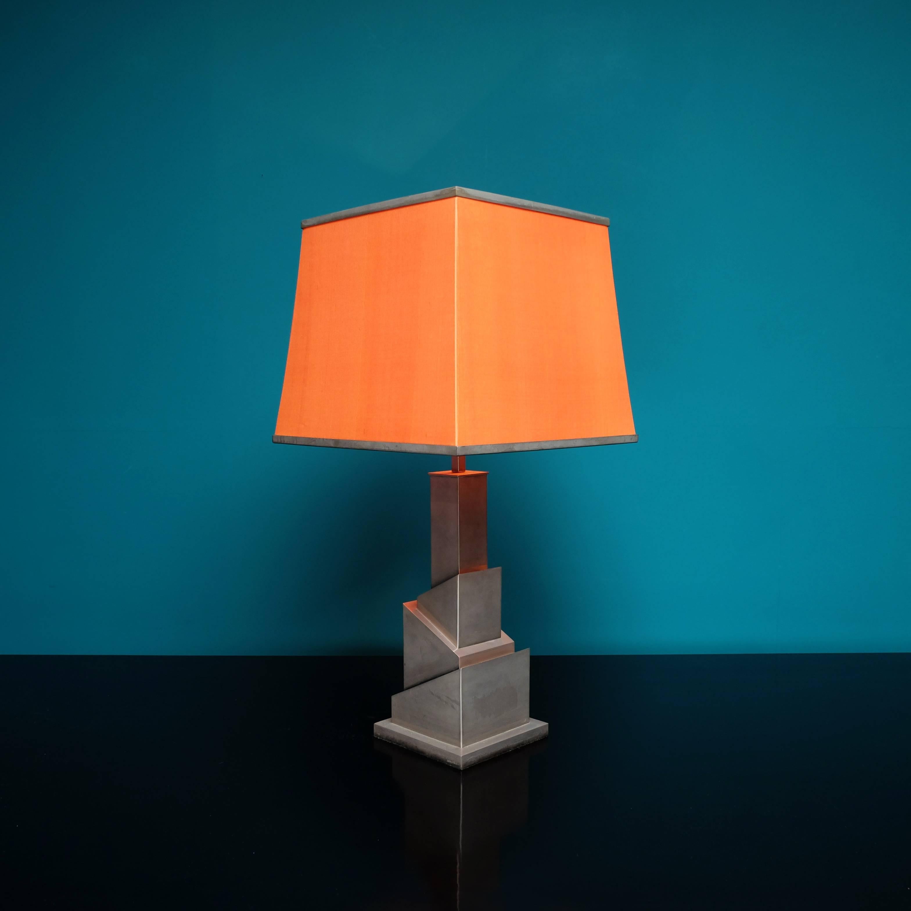 Sculptural nickel-plated table lamp in original condition with orange silk shade.