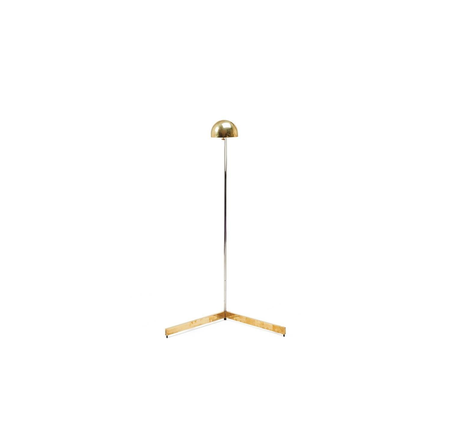 This reading lamp with a brass dimmer switch has a brass V-shaped base and semi-spherical shade that is supported by an arching chrome stem with pivot point that allows the lamp to rotate almost 360 degrees. The combination of metals and shapes make