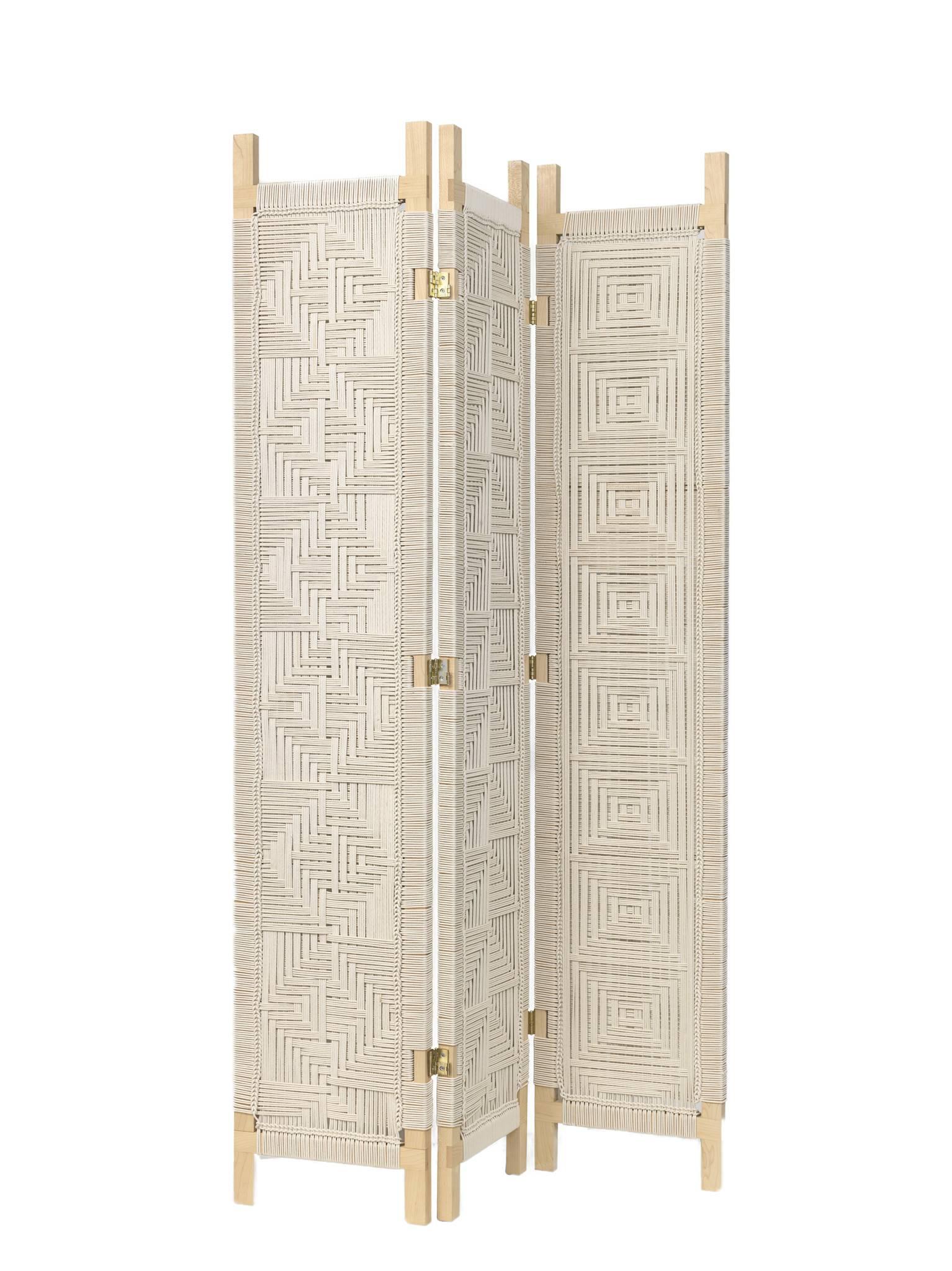 The Lassen room divider features lap joint detailing on an oiled maple frame with three handwoven panels. The divider's hinges allow each partition to swing forwards and backwards for various configurations. The cotton cord is knotted directly onto